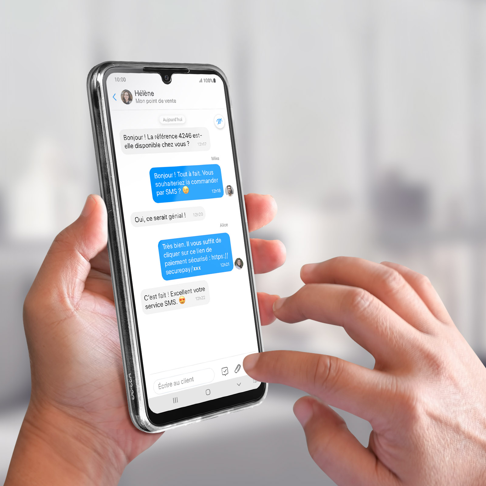 Une main tient un téléphone affichant une conversation de chat. L'arrière-plan est flou.