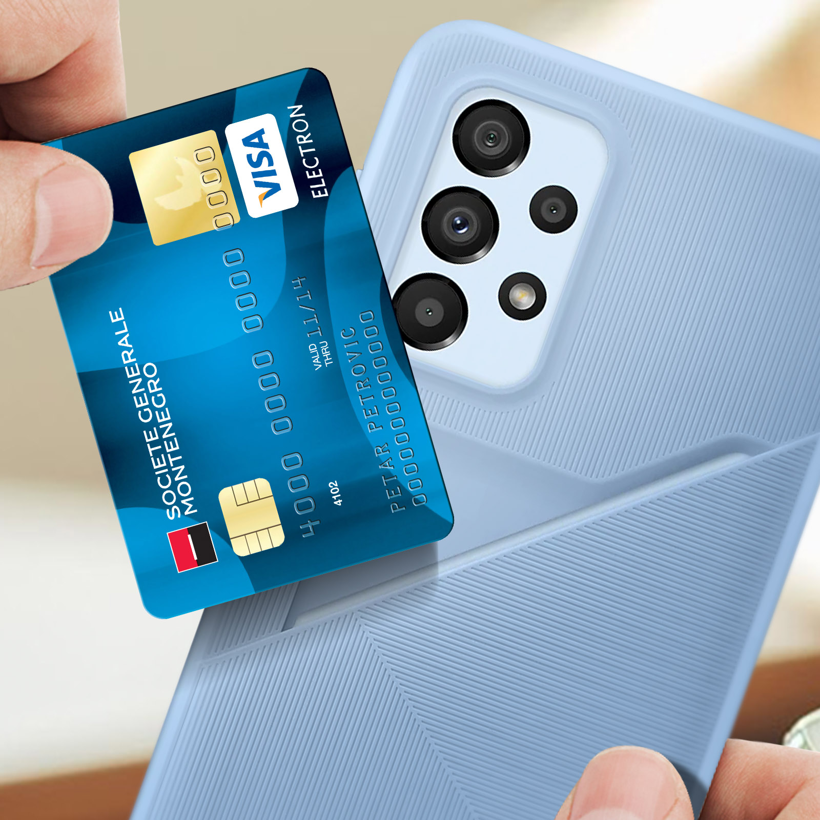 Mano sosteniendo una tarjeta Visa azul sobre una funda de teléfono azul claro. Un teléfono con cámaras es visible.