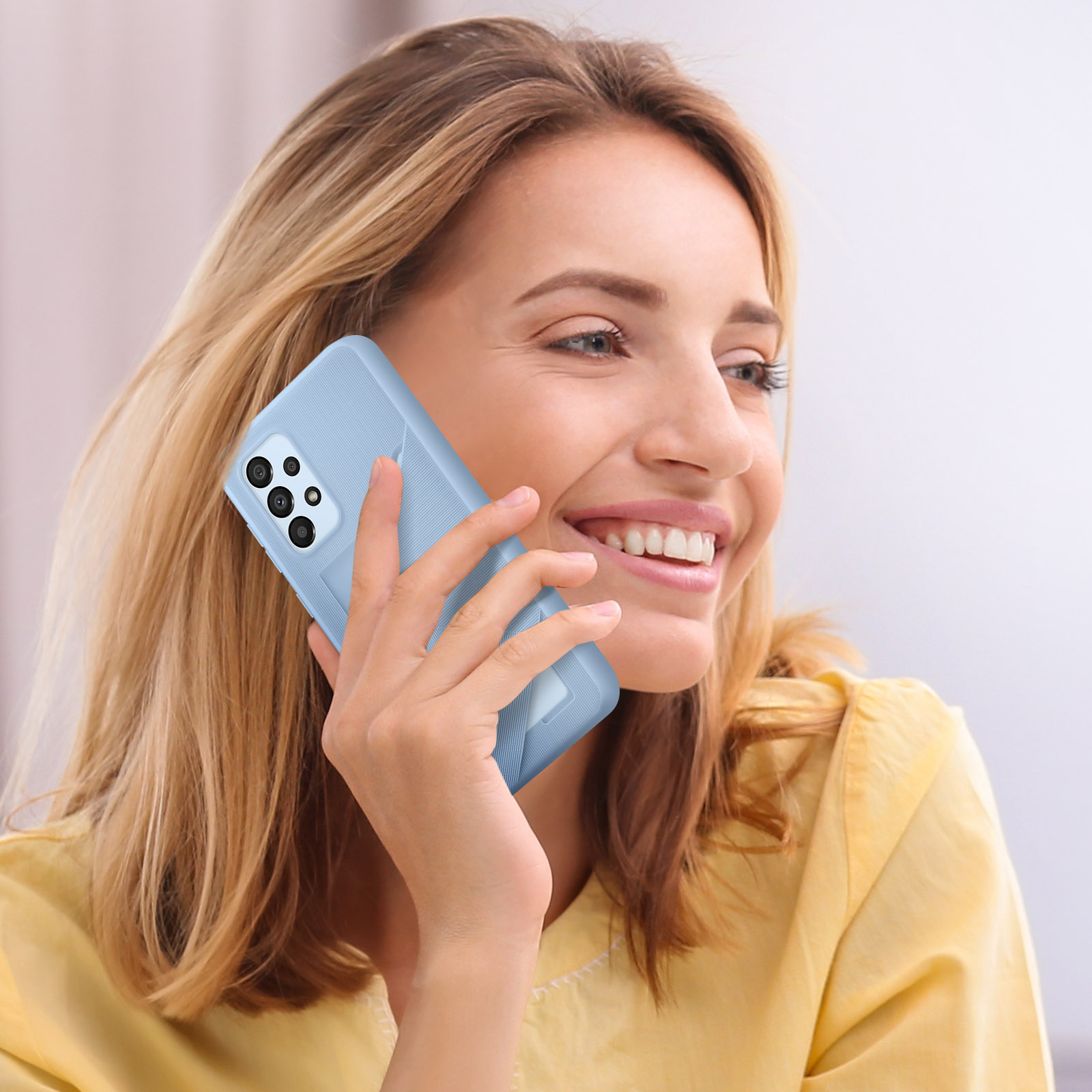 Mujer sonriendo mientras sostiene una funda de teléfono azul. La funda está en el teléfono.