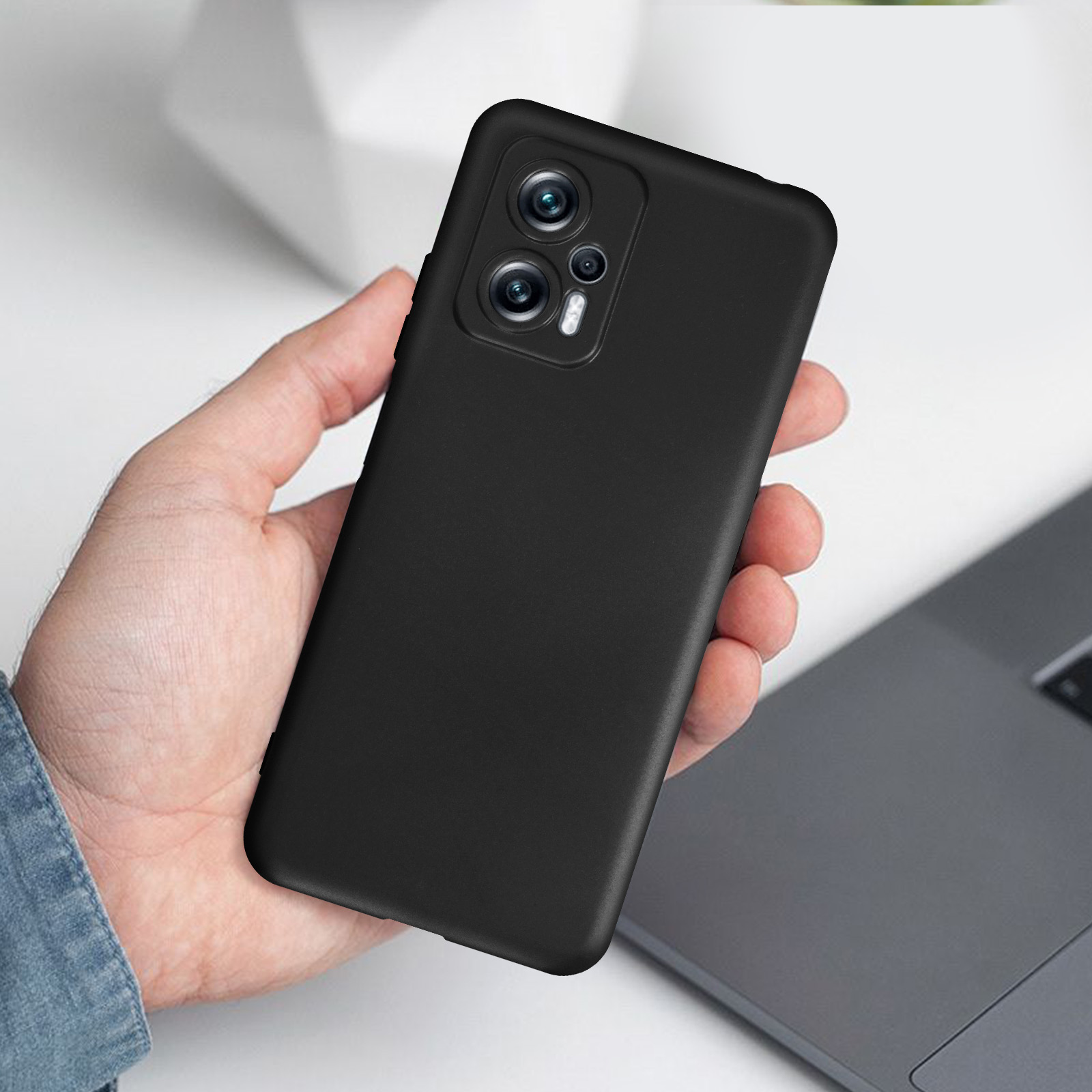 Eine Hand hält ein schwarzes Telefon, das nach oben geneigt ist und die Rückseite mit Kamera zeigt.