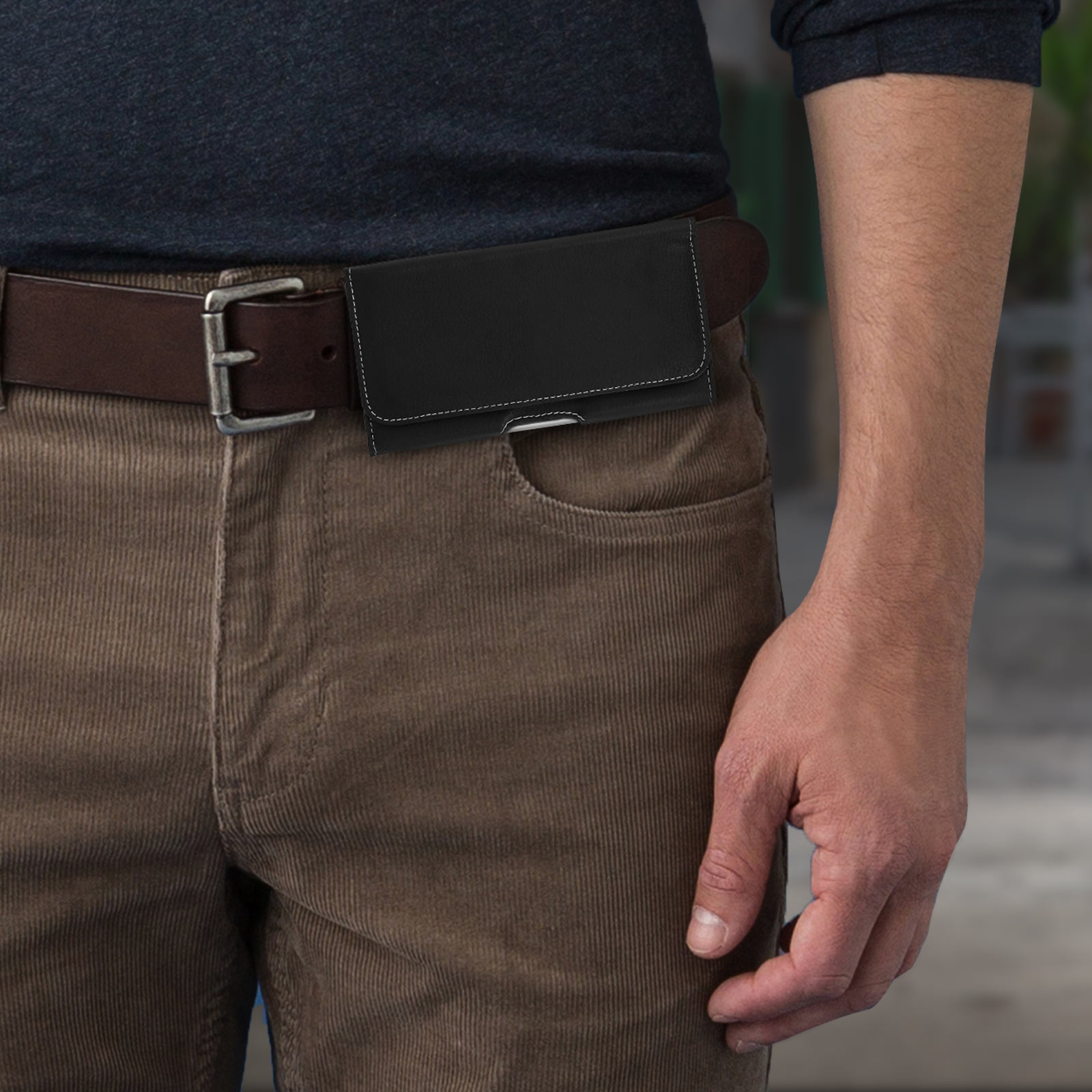Custodia nera per telefono sulla cintura di un uomo. L'uomo indossa pantaloni marroni.