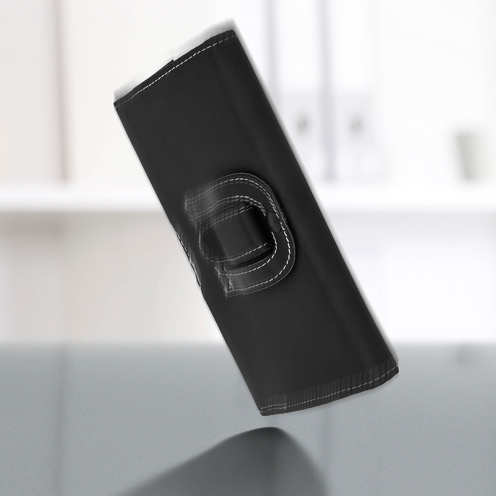 Custodia nera per telefono che cade. Ha un anello per tenere. Lo sfondo è bianco sfocato.