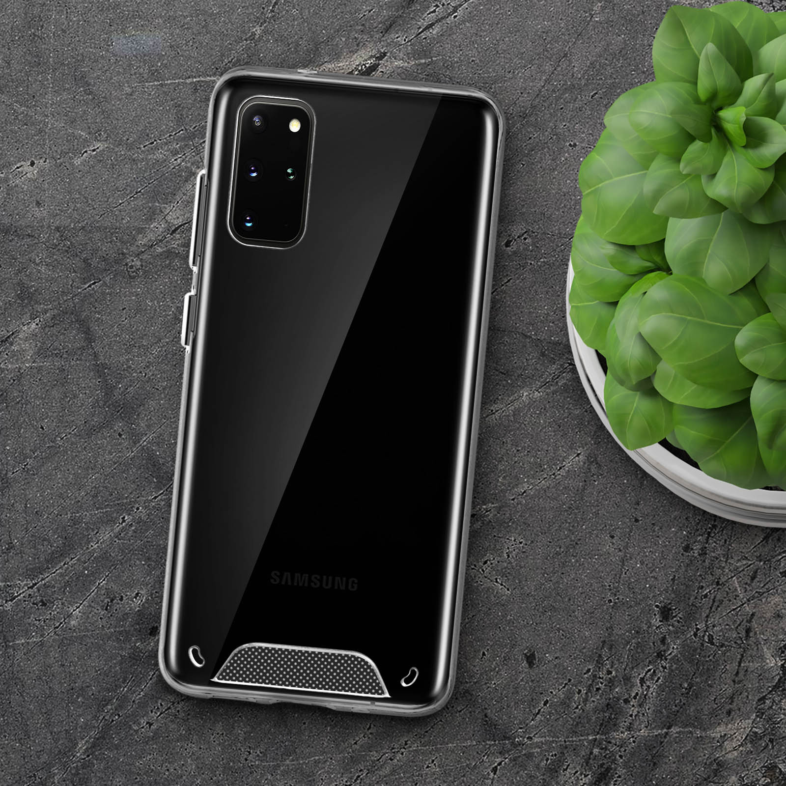 Un telefono in una custodia trasparente su una superficie di pietra scura. Una pianta sullo sfondo.