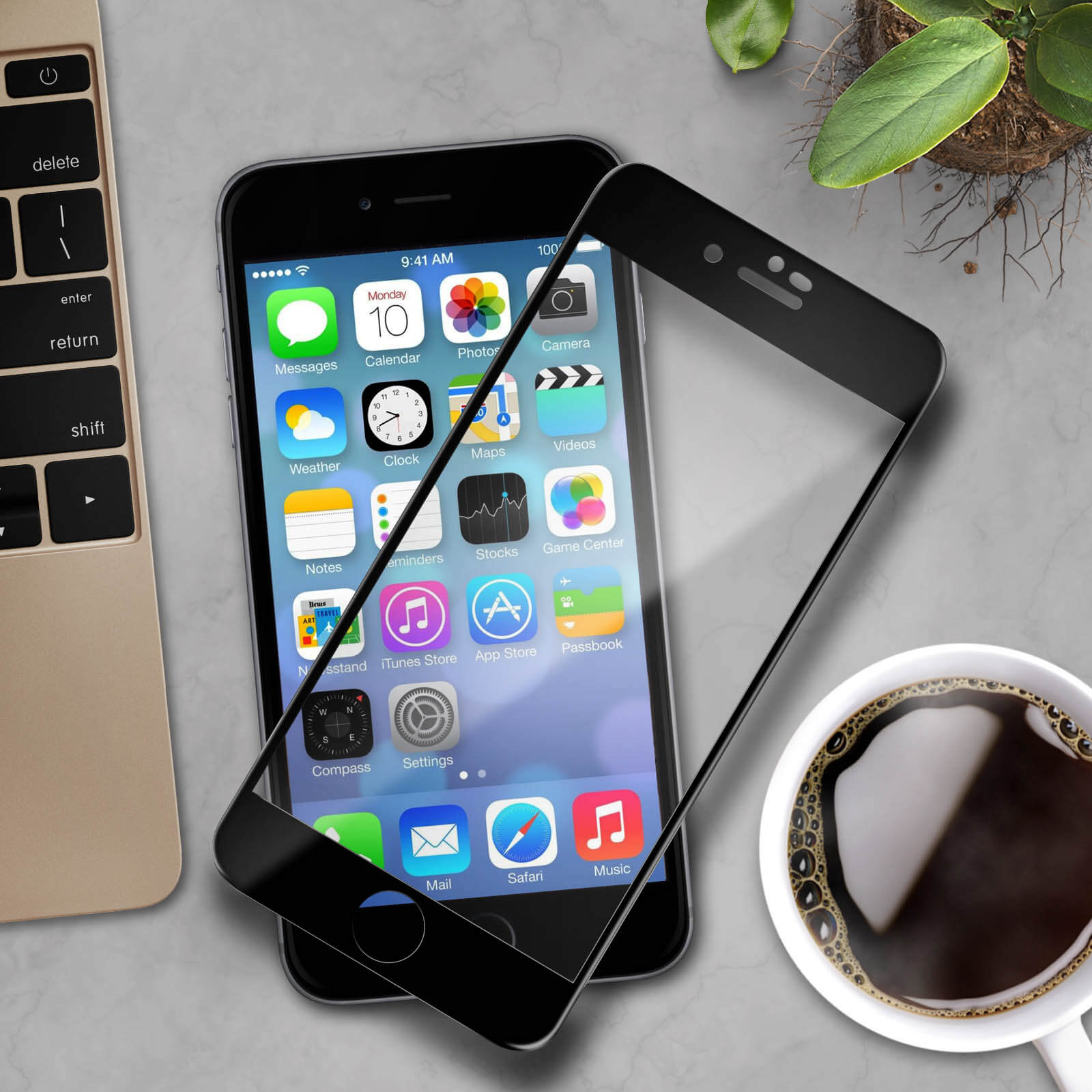 Uno smartphone con una protezione per lo schermo, su una scrivania con tastiera, pianta e caffè.