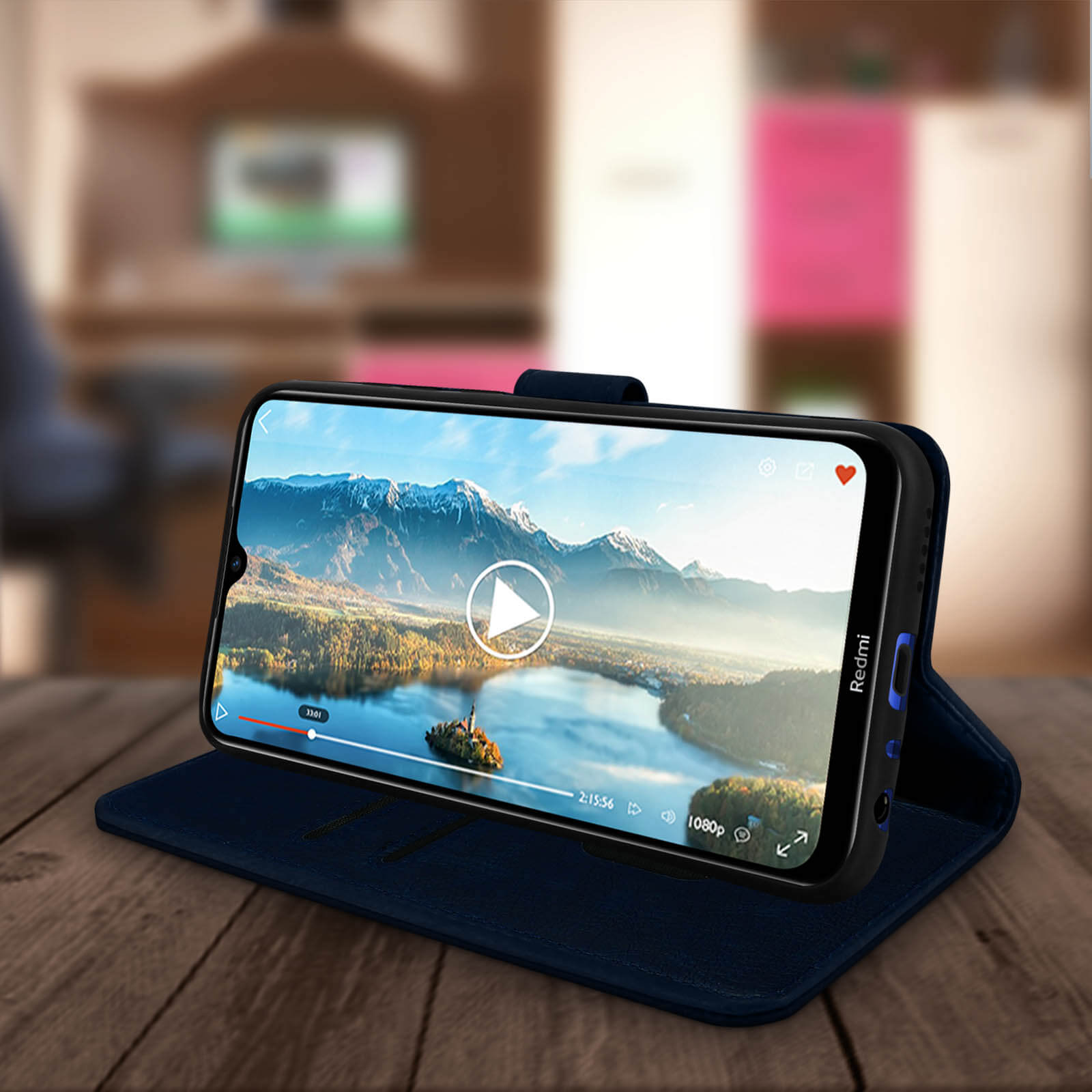 Telefono su un supporto, mostra un video di un lago di montagna. Lo sfondo è una stanza sfocata.