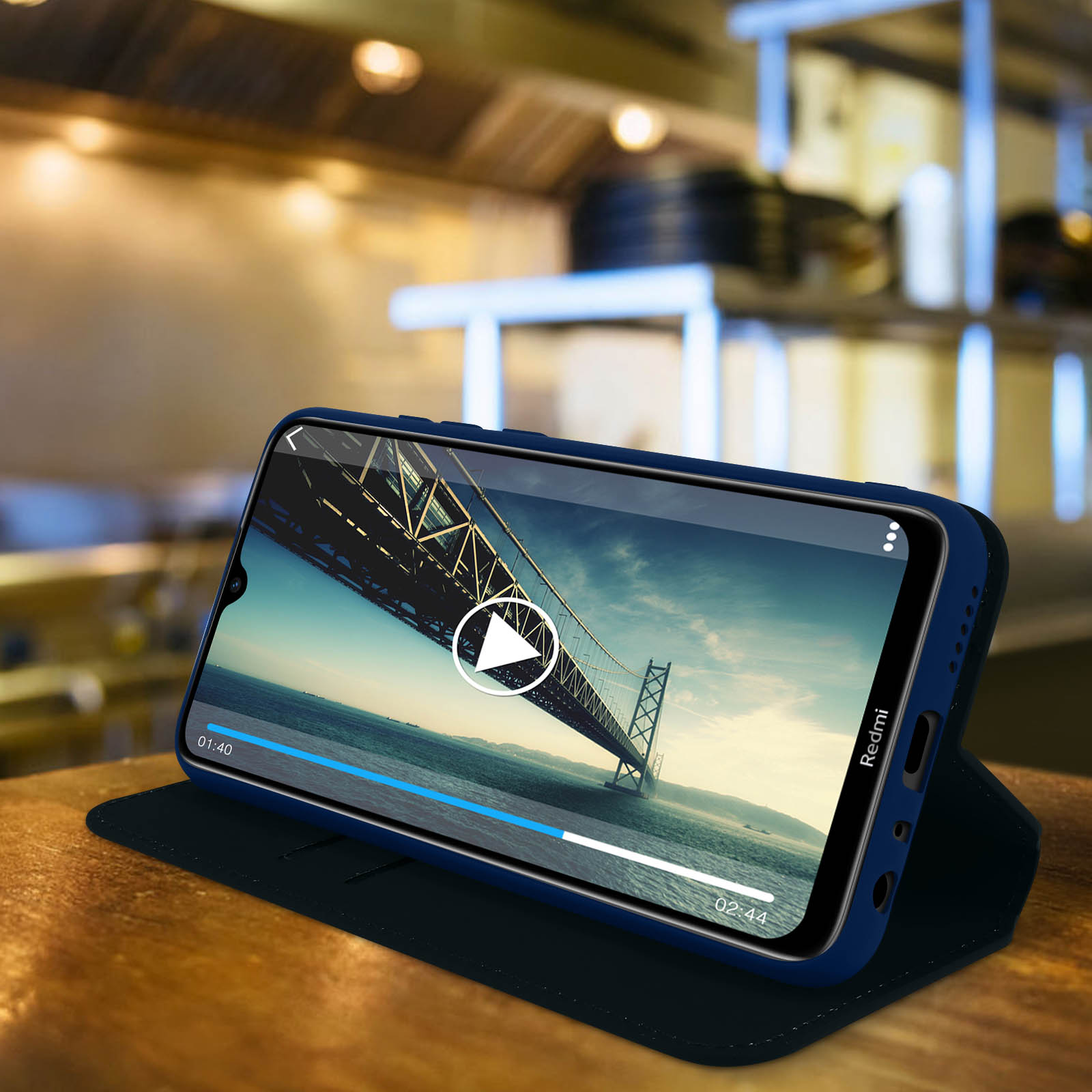 Telefono su un supporto. Il telefono ha un video in riproduzione. Sfondo cucina.