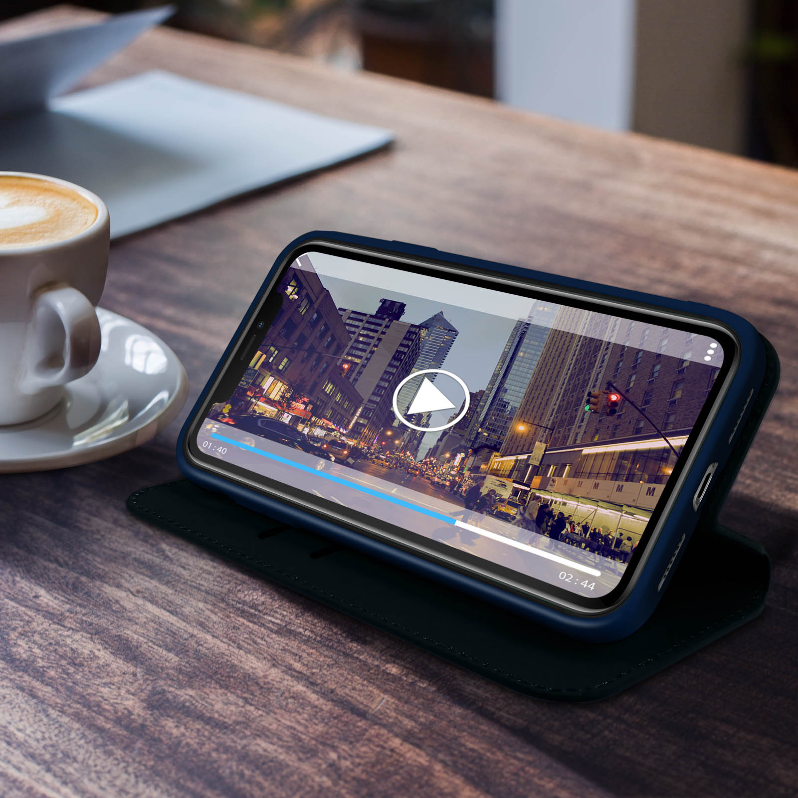 Telefoon op tafel met video van stad 's nachts. Koffiekopje links.