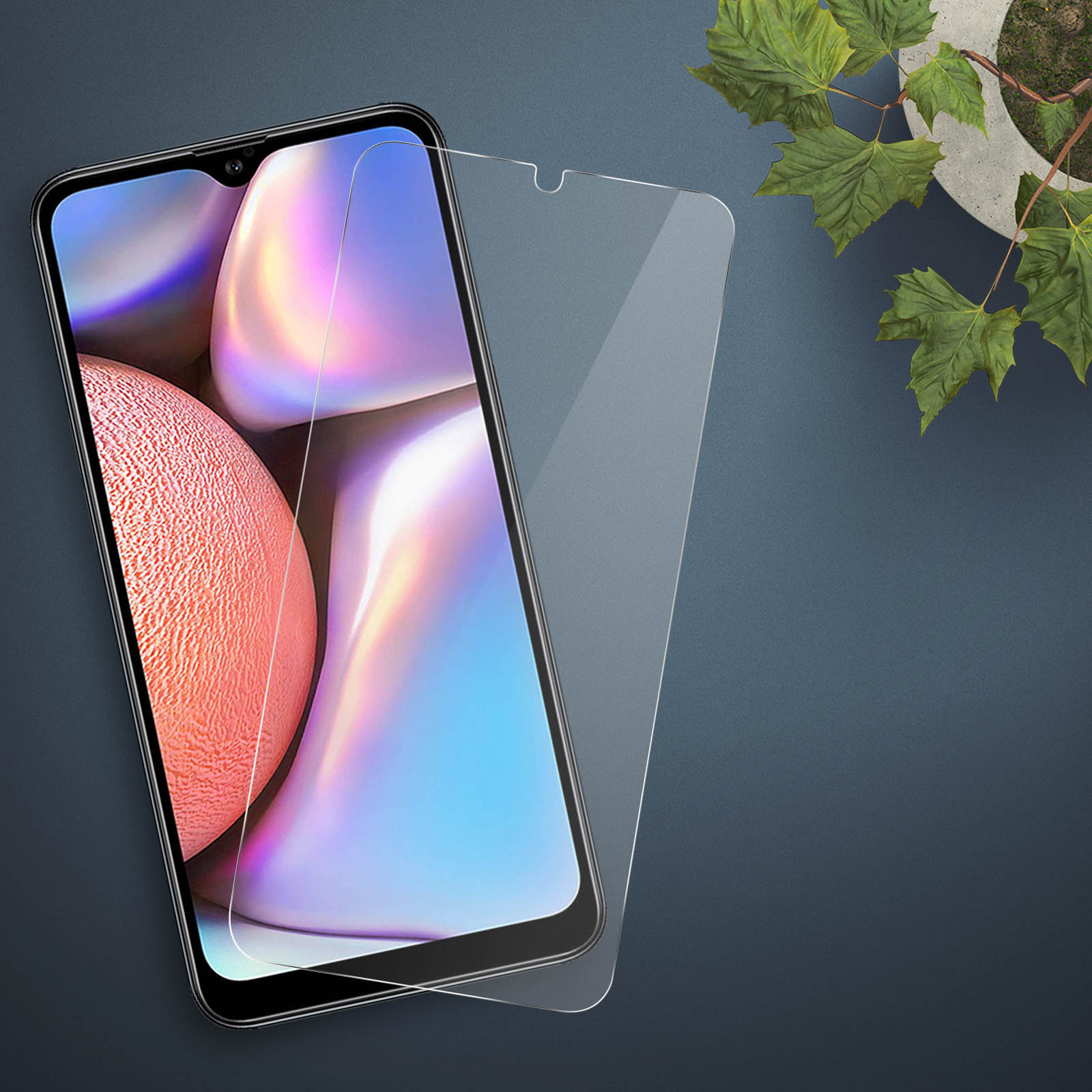 Een telefoon met een schermbeschermer. De telefoon staat op een donkerblauwe ondergrond. Plant op de achtergrond.