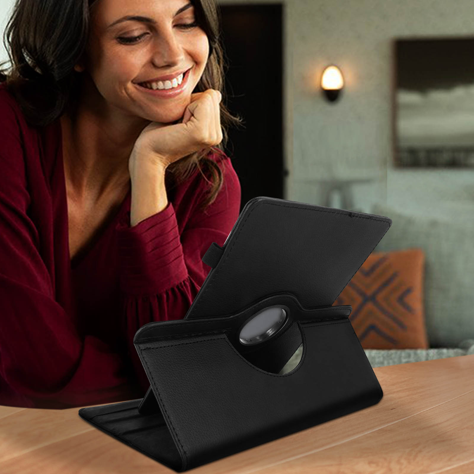 Donna sorridente mentre guarda un tablet su un supporto nero. Appoggia il mento sulla mano.