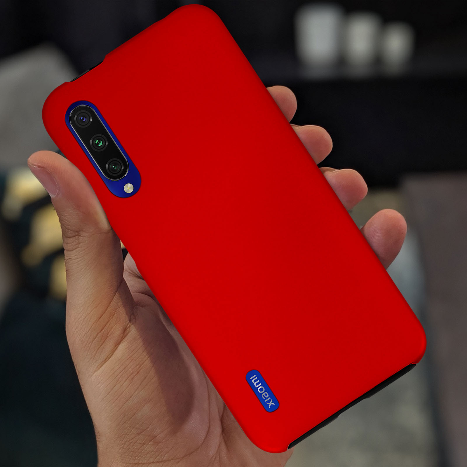Un telefono rosso tenuto in mano. Il telefono ha tre obiettivi e un logo bianco.