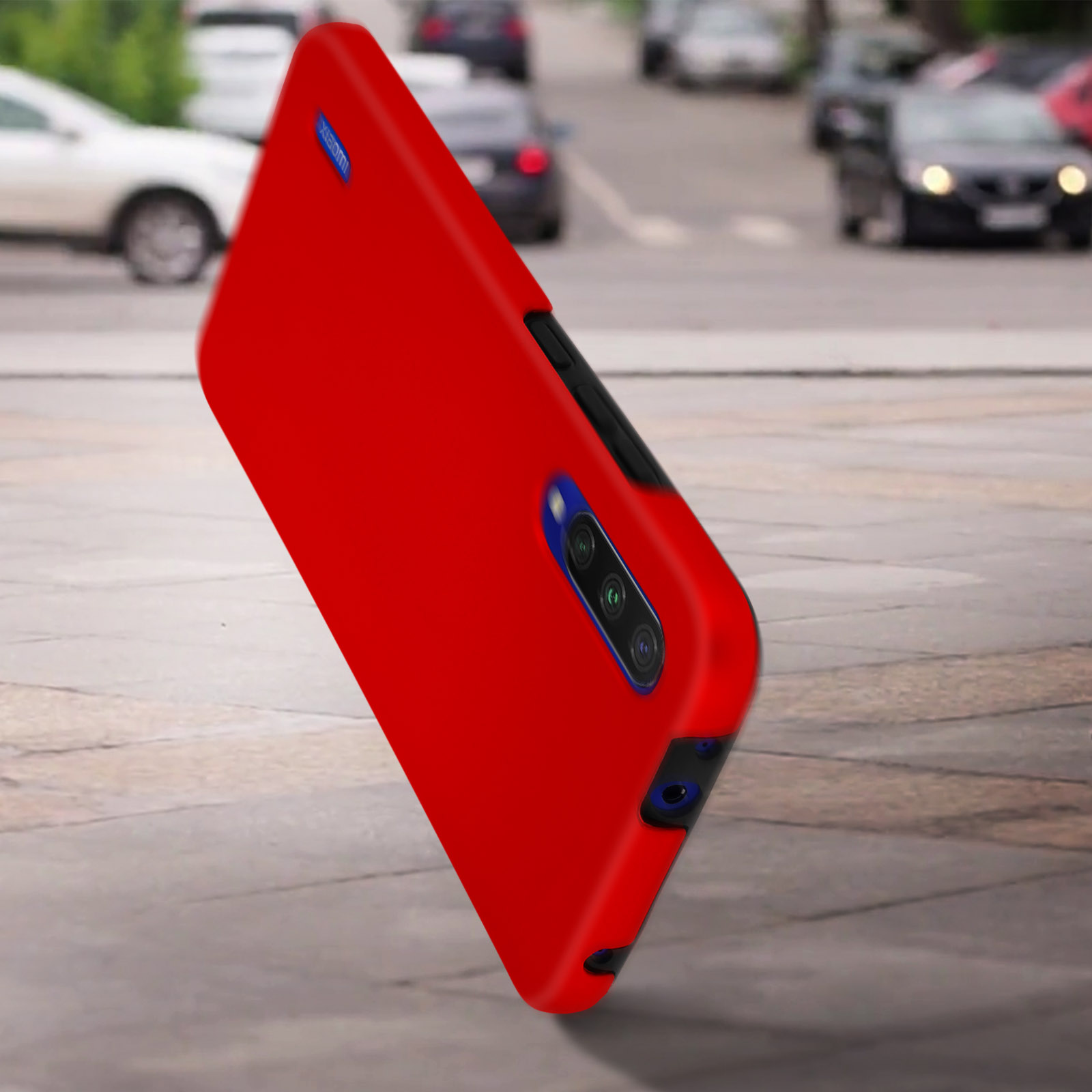 Custodia per telefono rossa su un marciapiede. La custodia è angolata, mostrando la fotocamera e un accento blu.