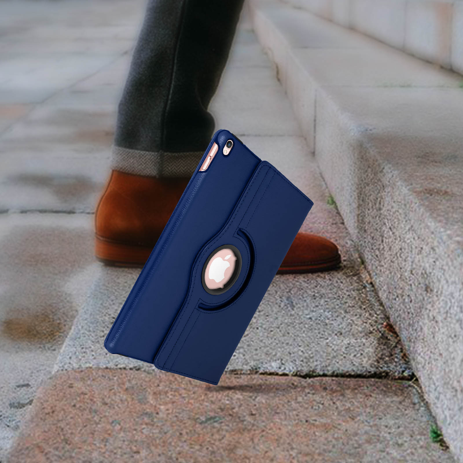 Tablet con custodia blu che cade dalle scale. Custodia aperta, con un anello. Scarpe marroni visibili.
