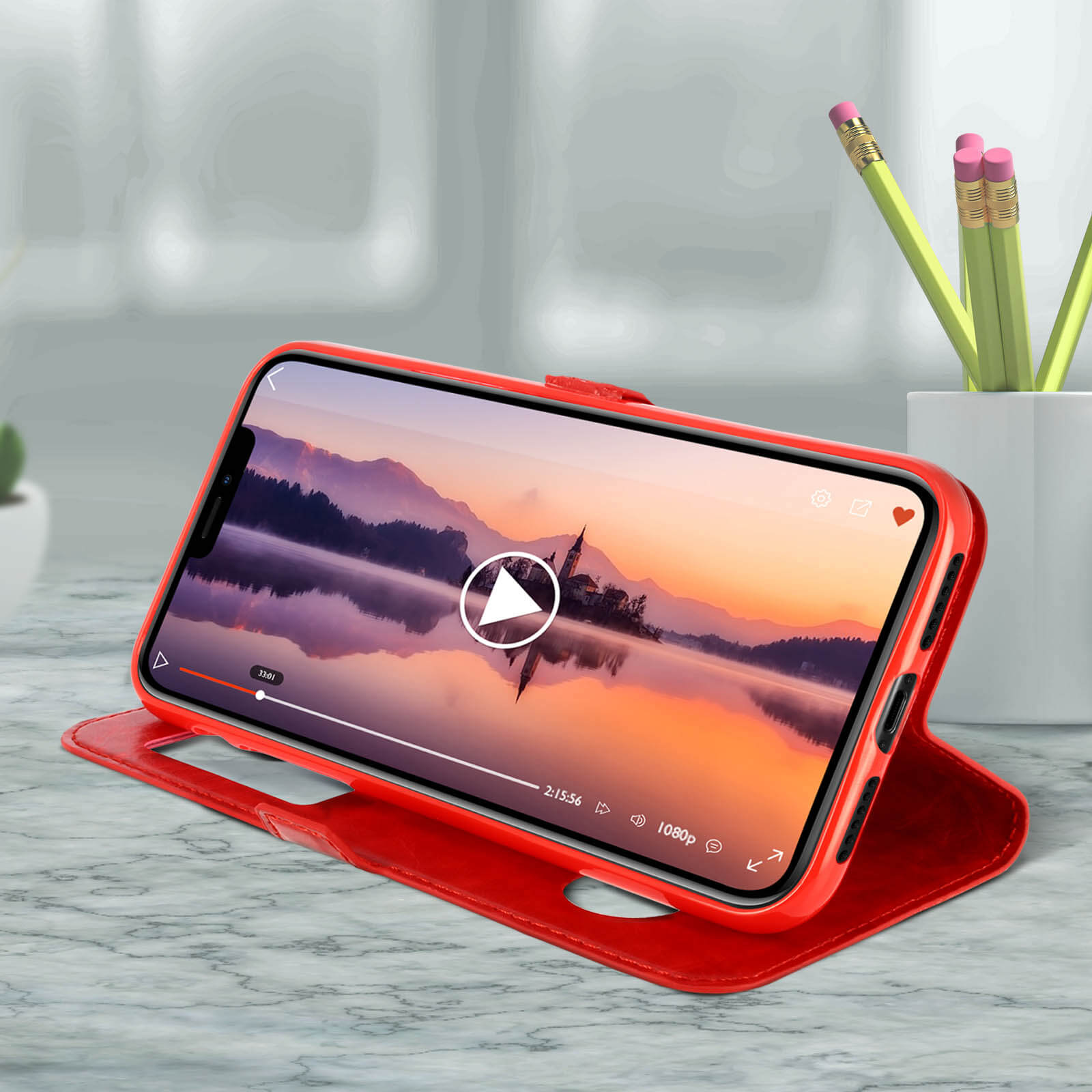 Rode telefoonhoes met een video, en potloden in een witte keramische pot.
