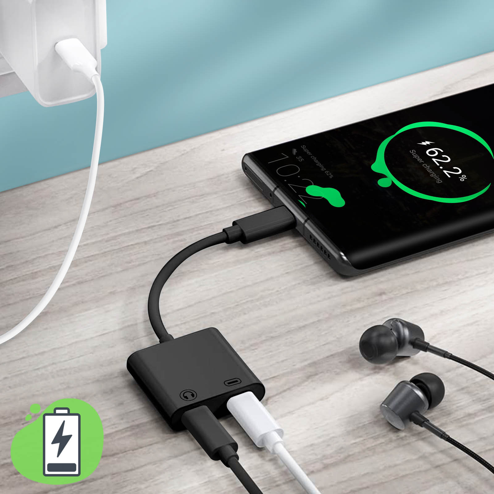 Telefono in carica con adattatore e splitter. Auricolari collegati su superficie in legno. Icona batteria.