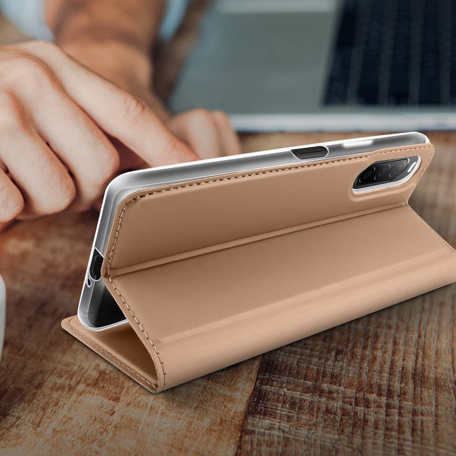 Smartphone in custodia marrone aperto, su tavolo di legno, con mano che si protende.