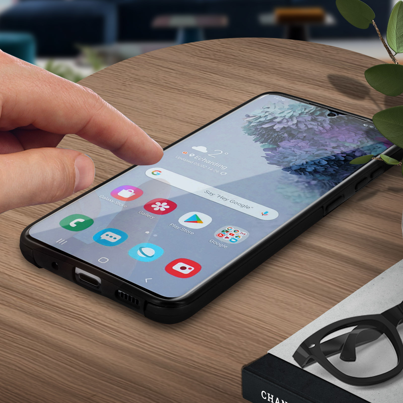 Un téléphone avec des icônes sur l'écran. Une main touche l'écran, et il y a des lunettes.