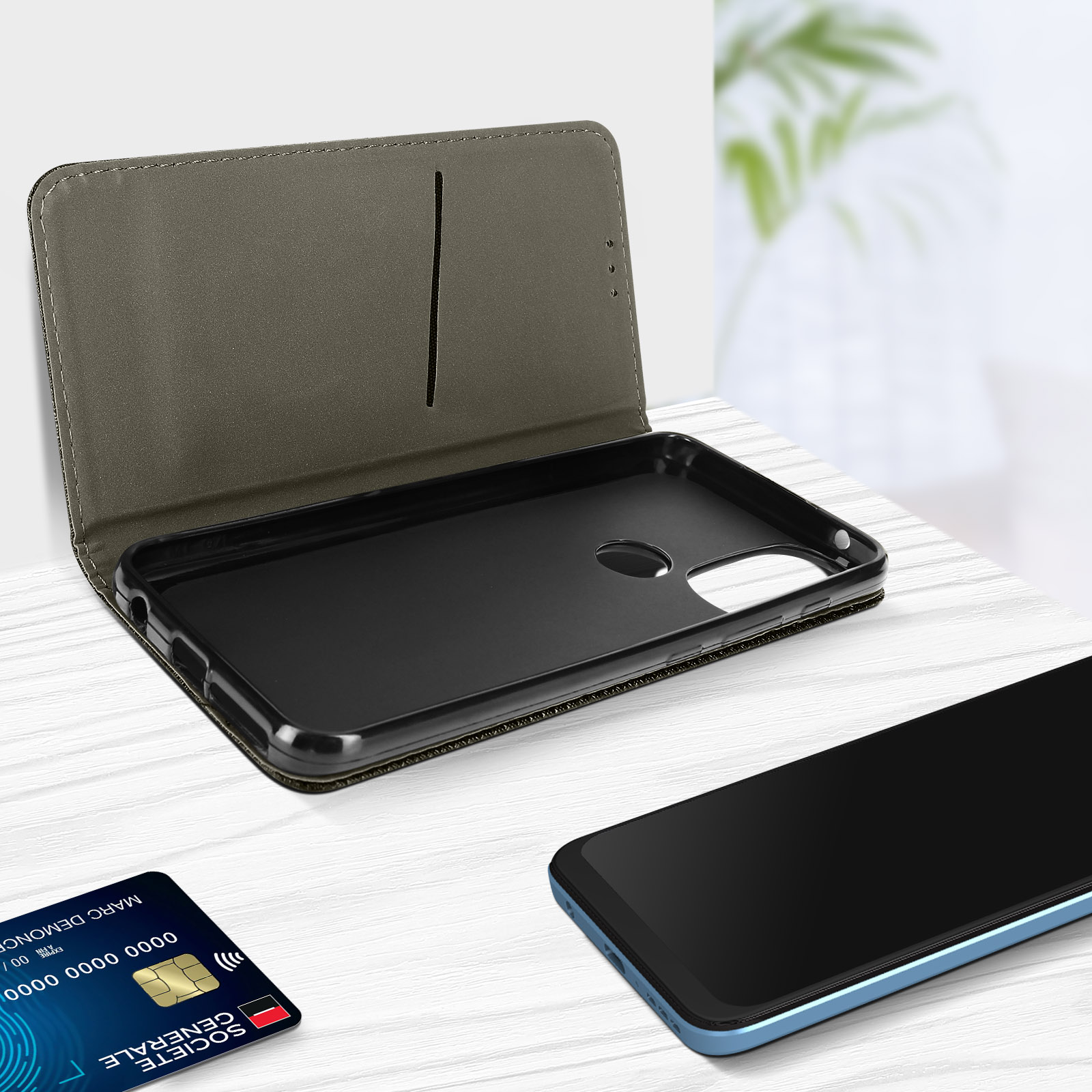 Custodia per telefono aperta con un telefono nero all'interno, con carta e carta di credito sul tavolo.