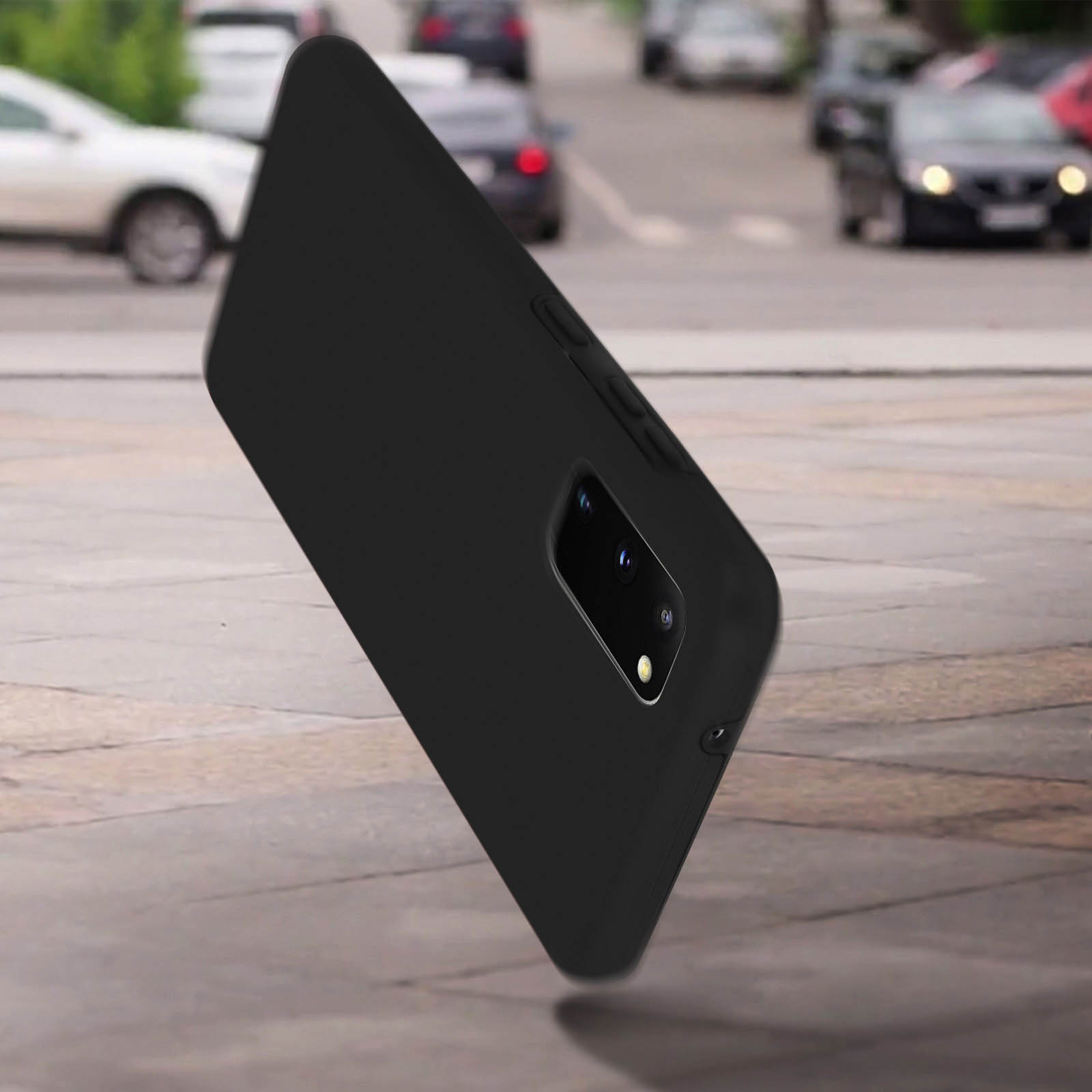 Een zwarte telefoonhoes op de grond, met auto's en een wazige achtergrond.