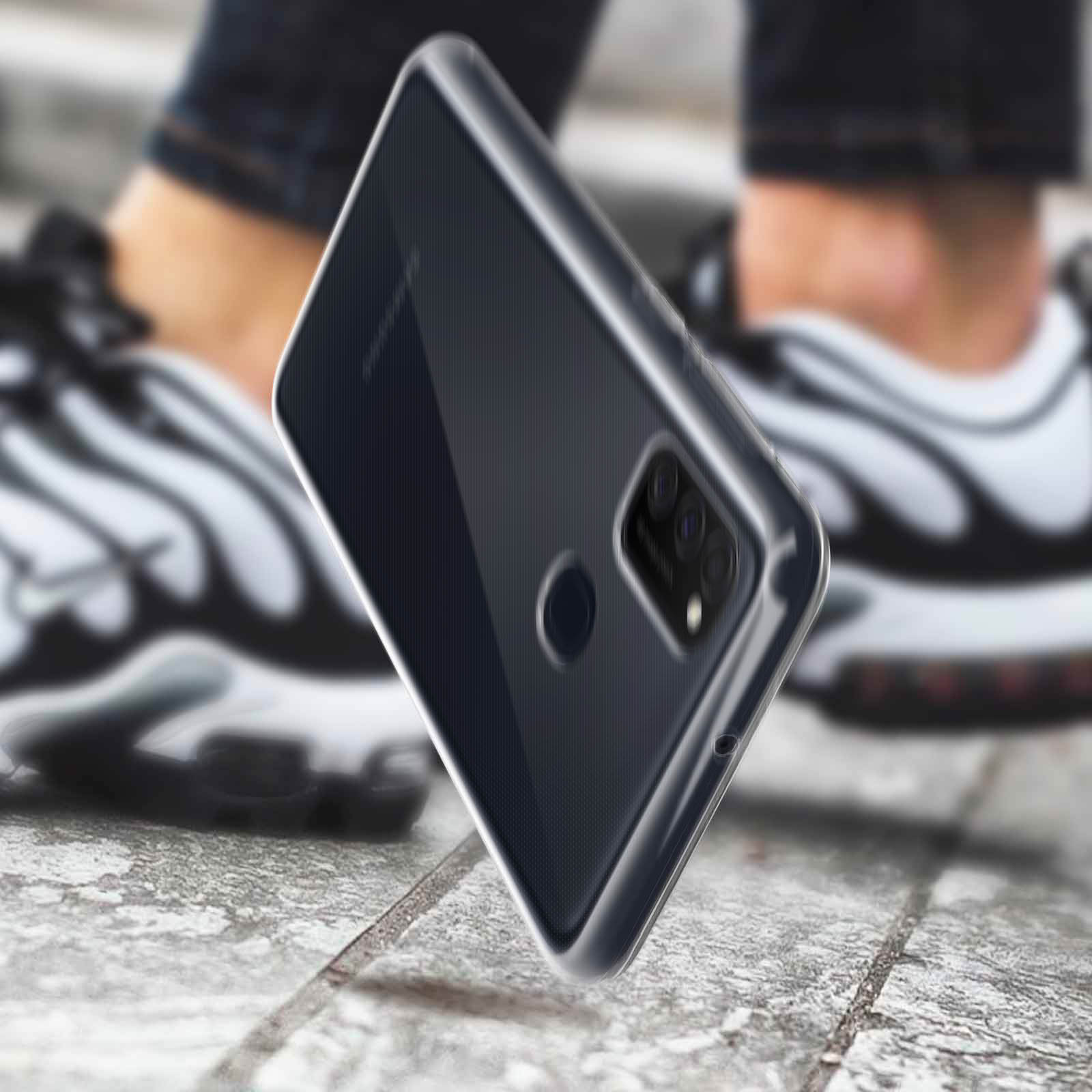 Custodia nera per telefono che cade, con gambe e pavimento visibili sullo sfondo.