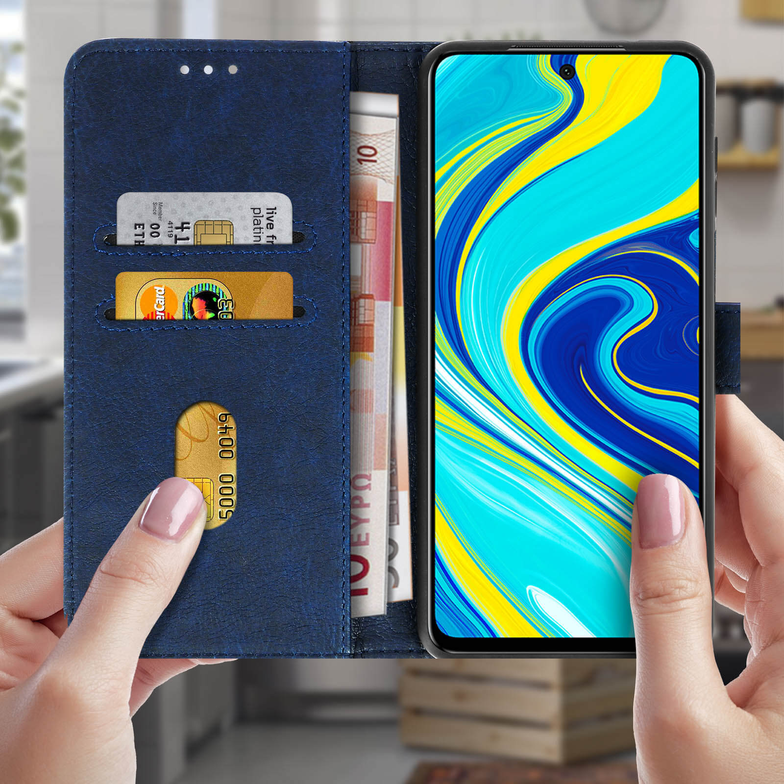 Un telefono in custodia blu con carte e denaro, tenuto in mano.
