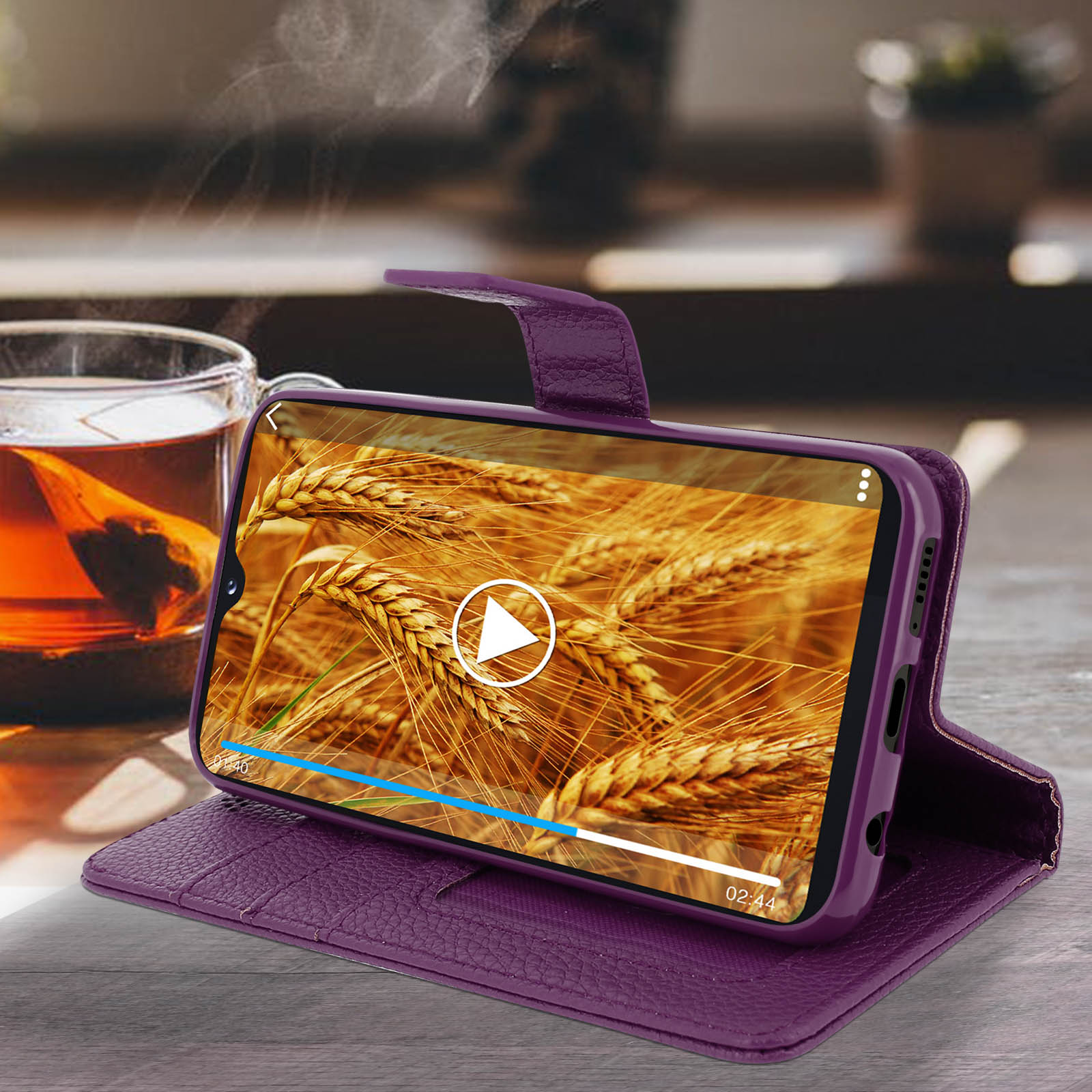 Een paarse telefoonhoes met een telefoon die een video van tarwe afspeelt op een houten tafel.