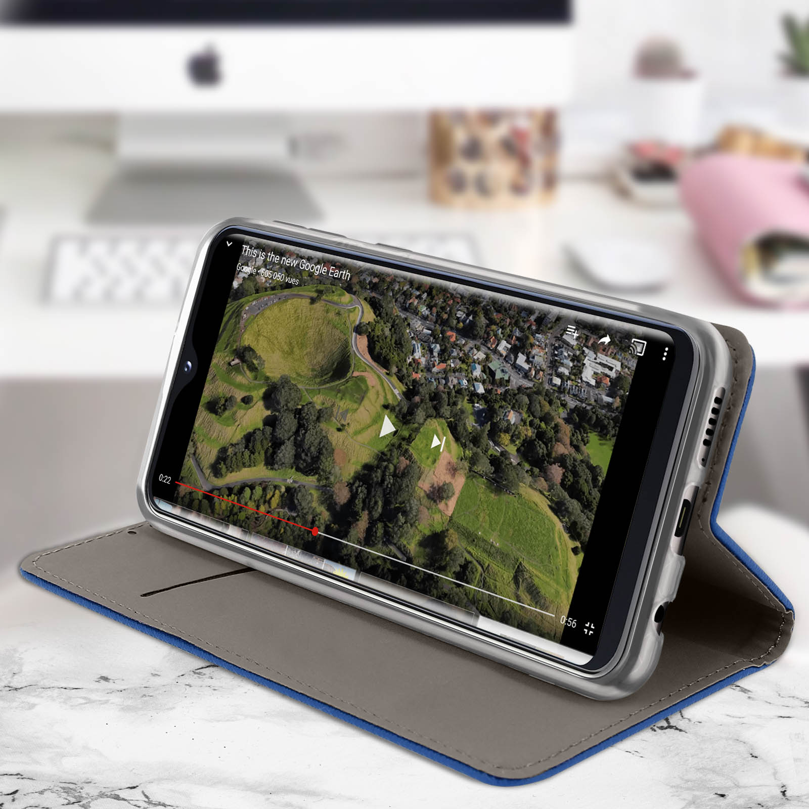Un téléphone dans un étui bleu est ouvert, diffusant une vidéo d'un paysage.