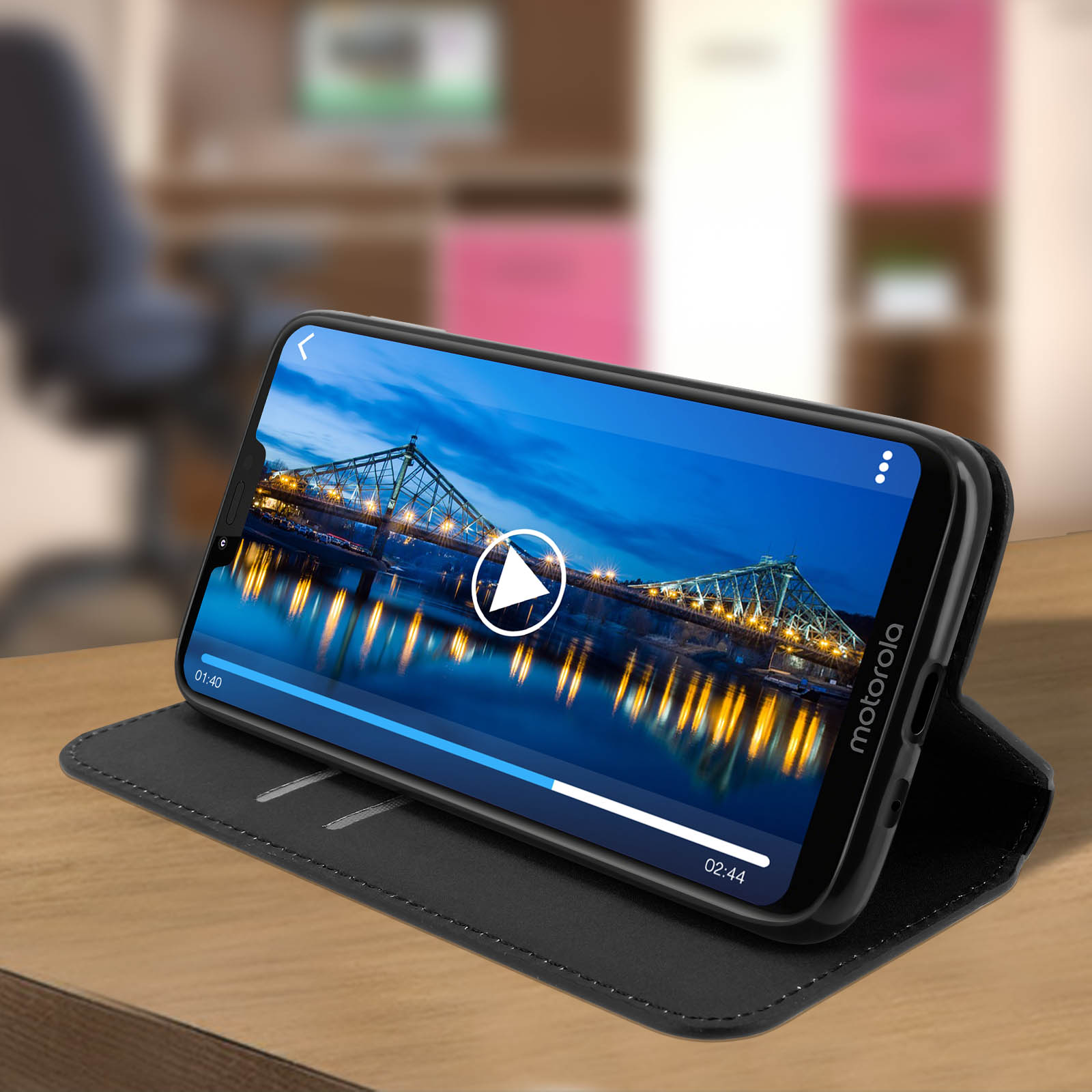 Un telefono mostra un video con un ponte. Un pulsante di riproduzione è sovrapposto. Il telefono è in una custodia a libro.