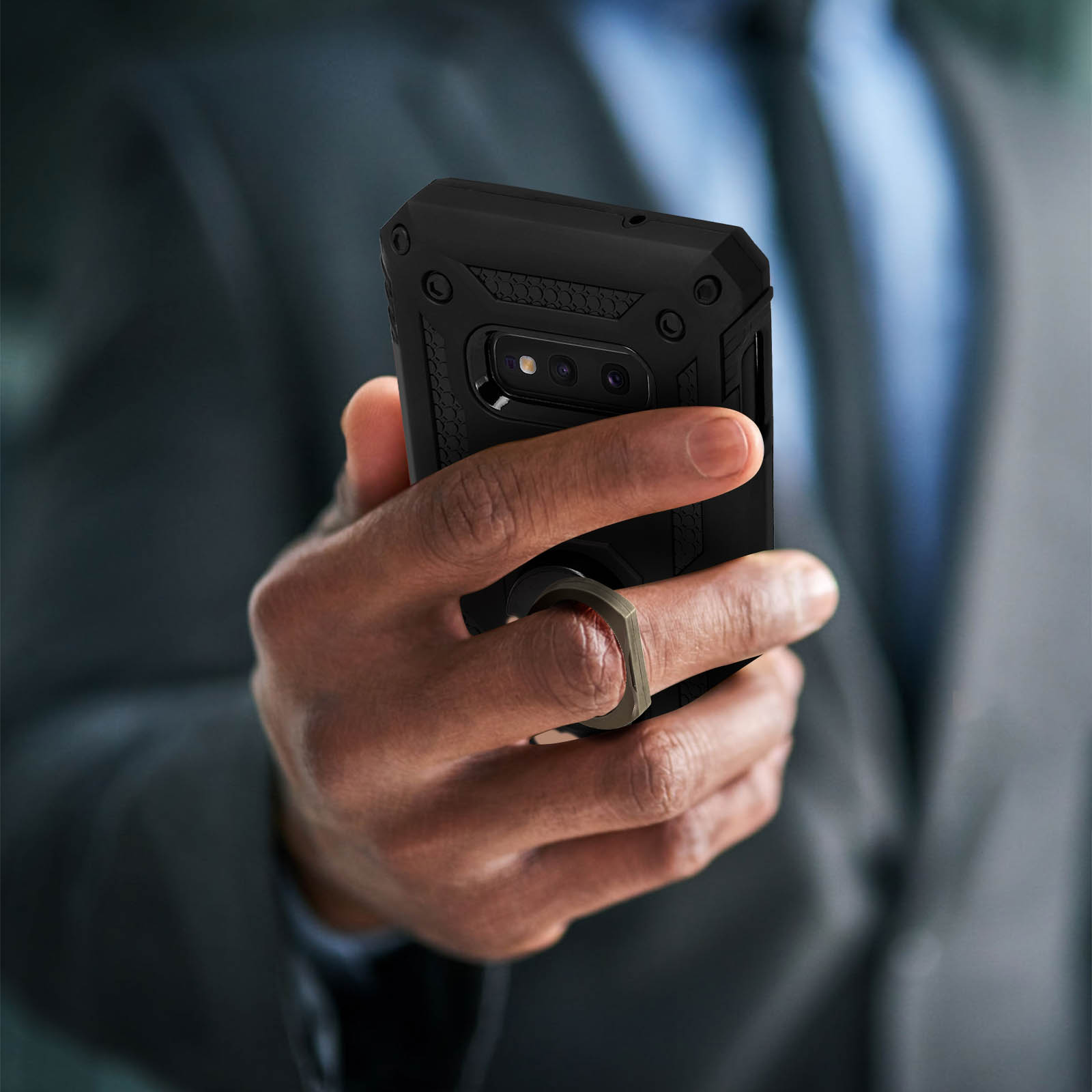 Une personne tient un téléphone avec une coque noire et un anneau de maintien.