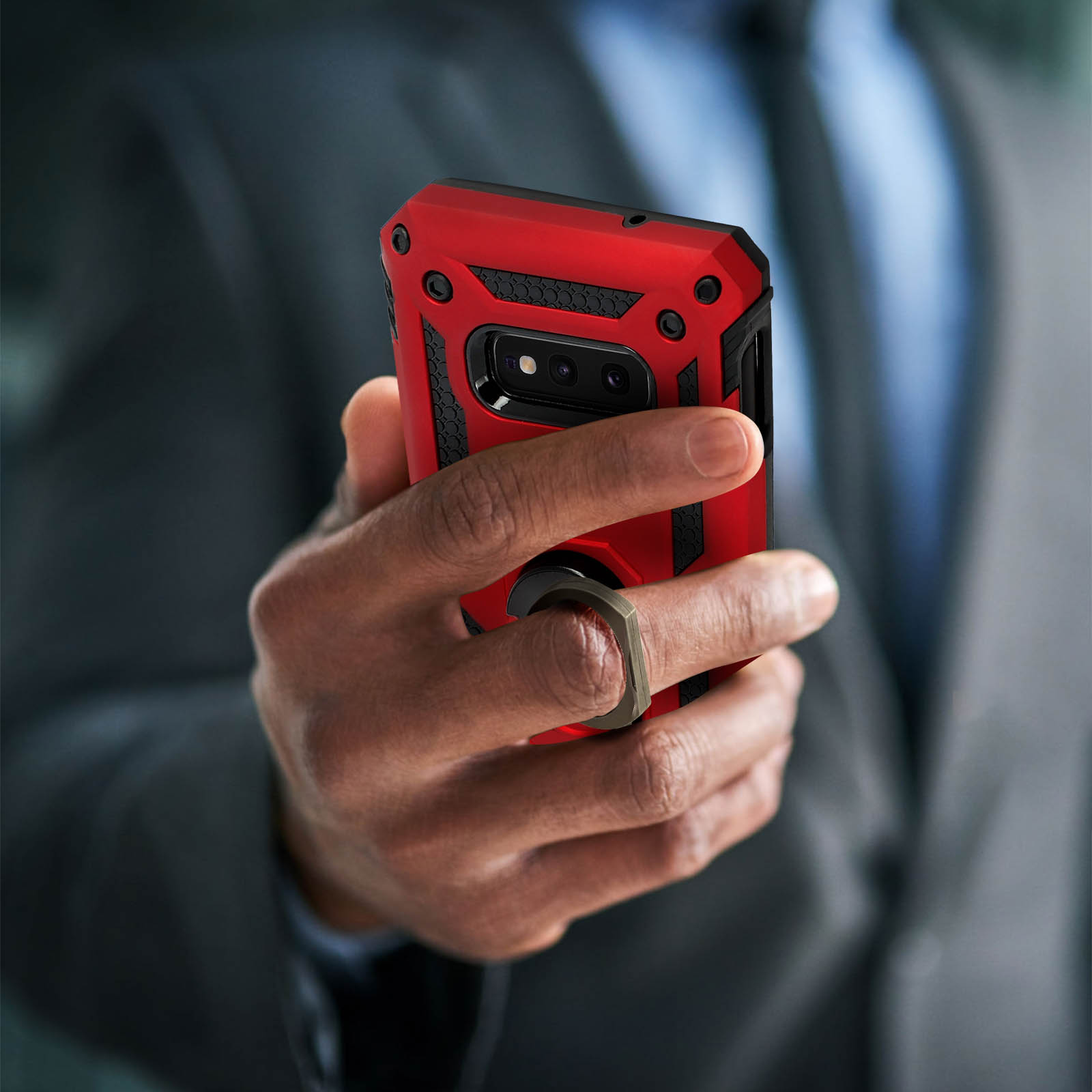 Un étui de téléphone rouge avec un support d'anneau, tenu par une personne. Un homme en costume est en arrière-plan.