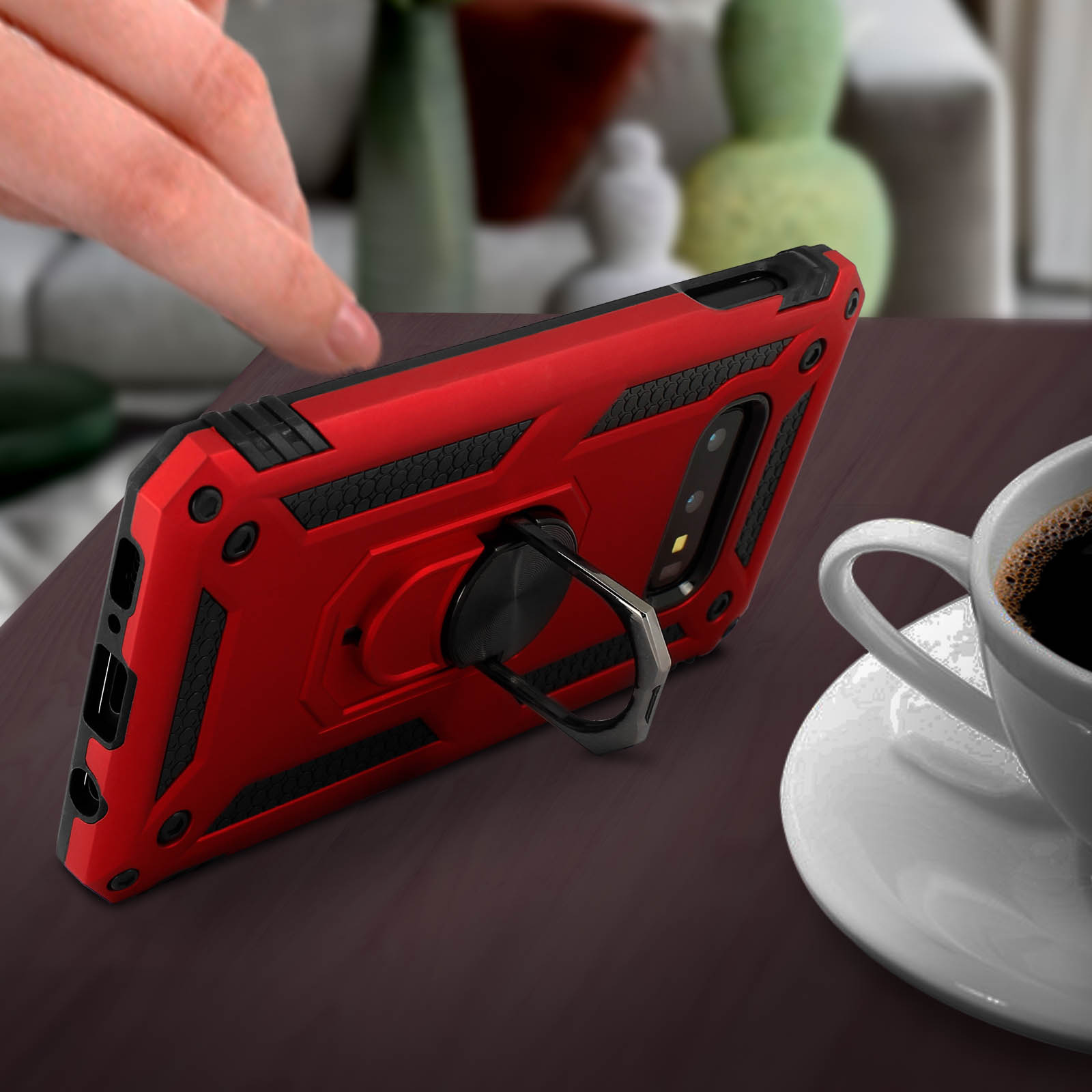 Coque rouge avec anneau, sur une table. Tasse de café à droite.