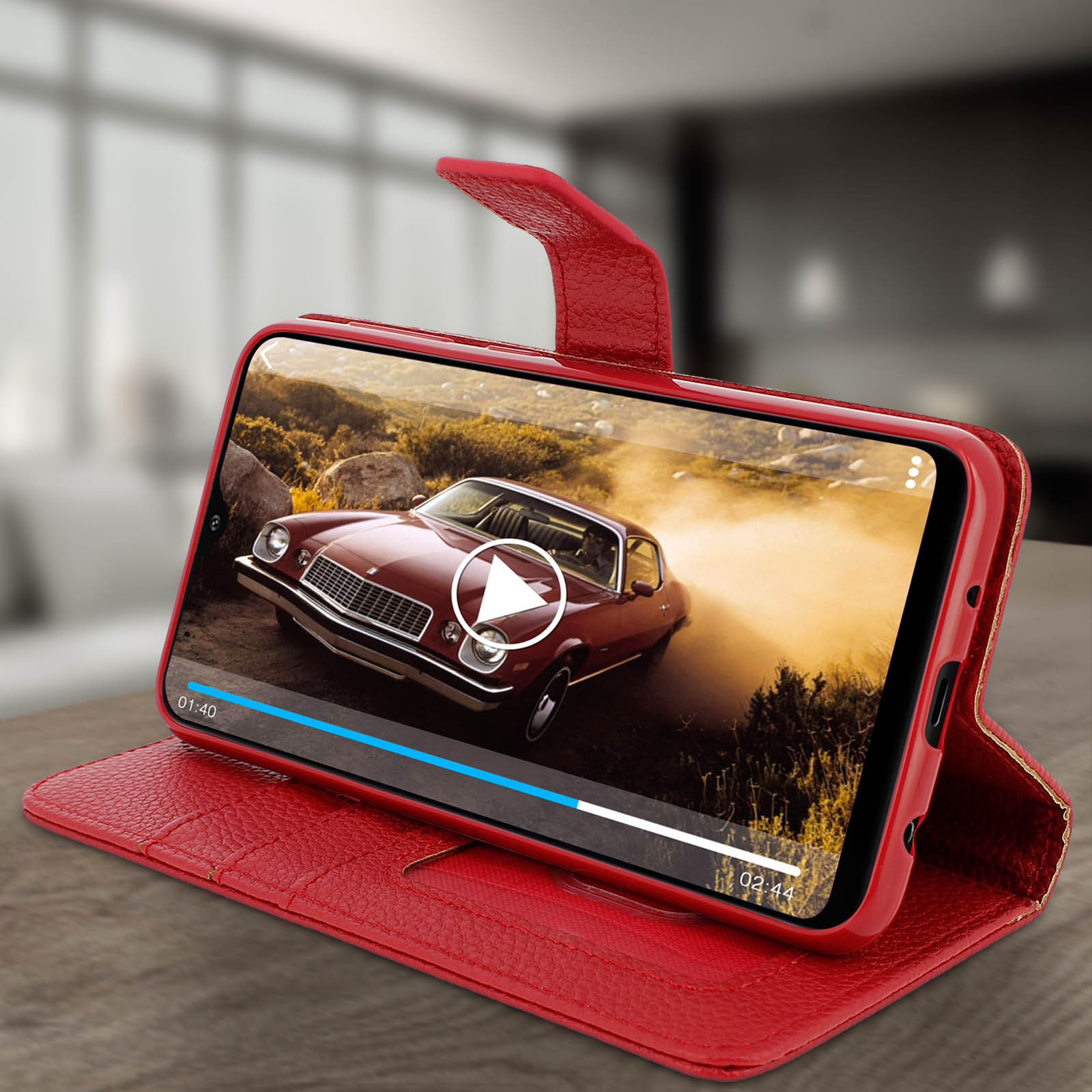 Rode telefoonhoes open, met autovideo. Leren textuur. Achtergrond: houten tafel.
