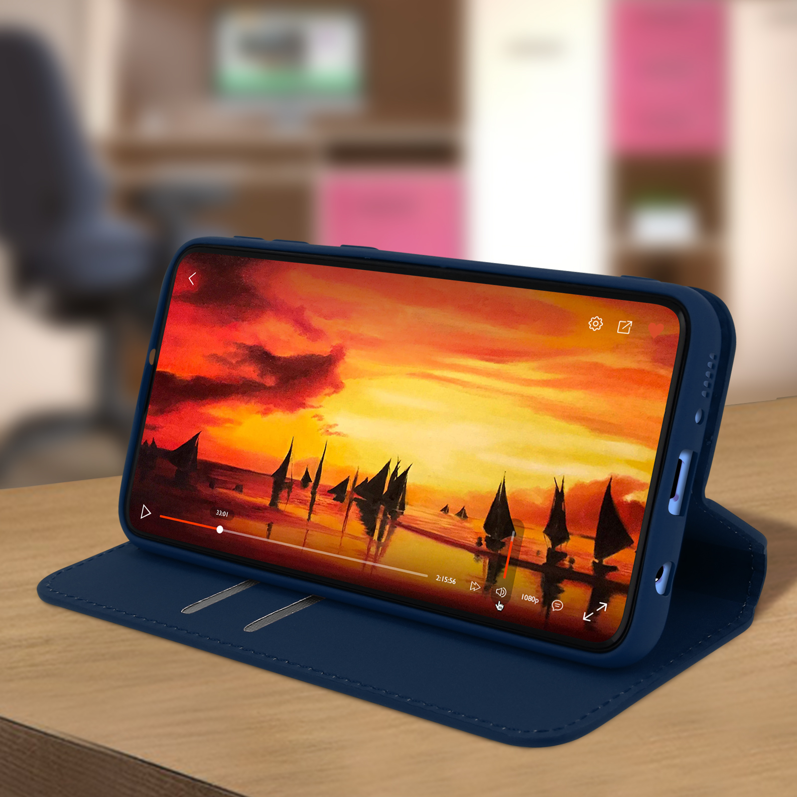 Een telefoon die een zonsondergangvideo weergeeft in een blauwe foliohoes op een tafel.