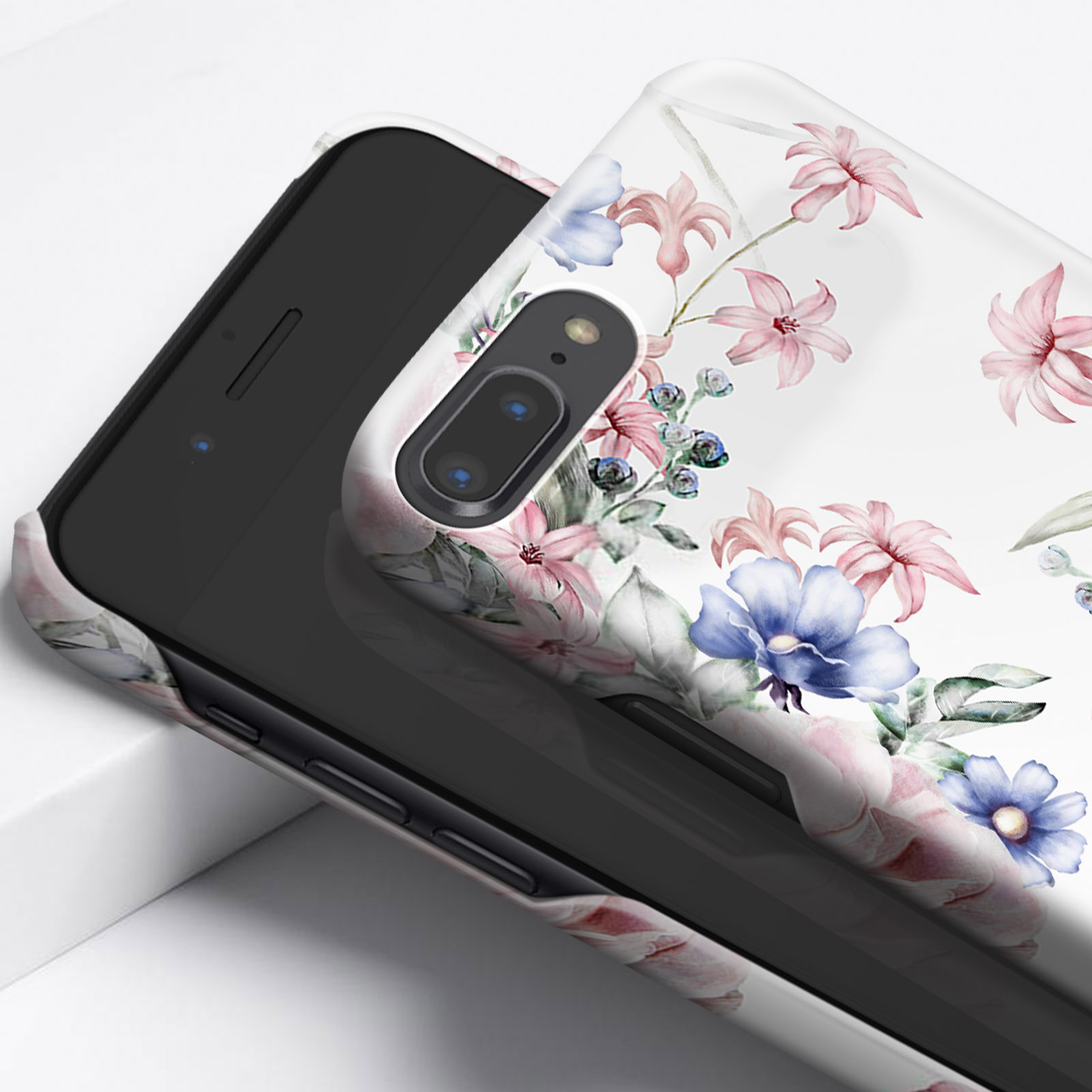 Telefono in una custodia floreale, angolato su una superficie bianca con sfondo sfocato.