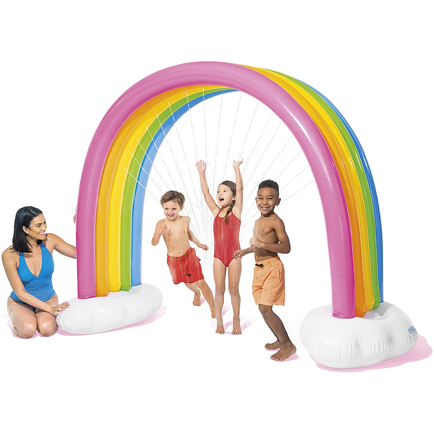 Kinder spielen unter einer Regenbogenspritze. Eine Frau schaut daneben zu.