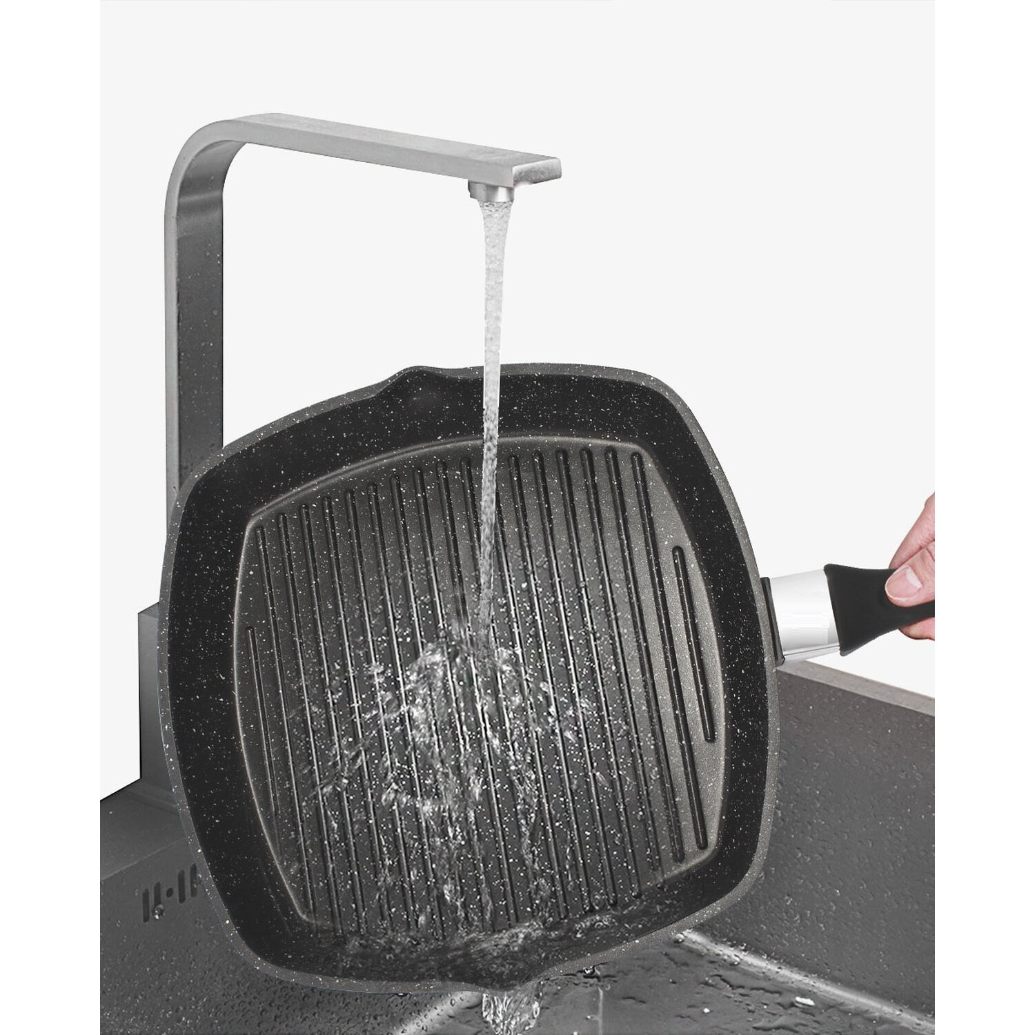 Wasser gießt auf eine schwarze Grillpfanne in einem Waschbecken.
