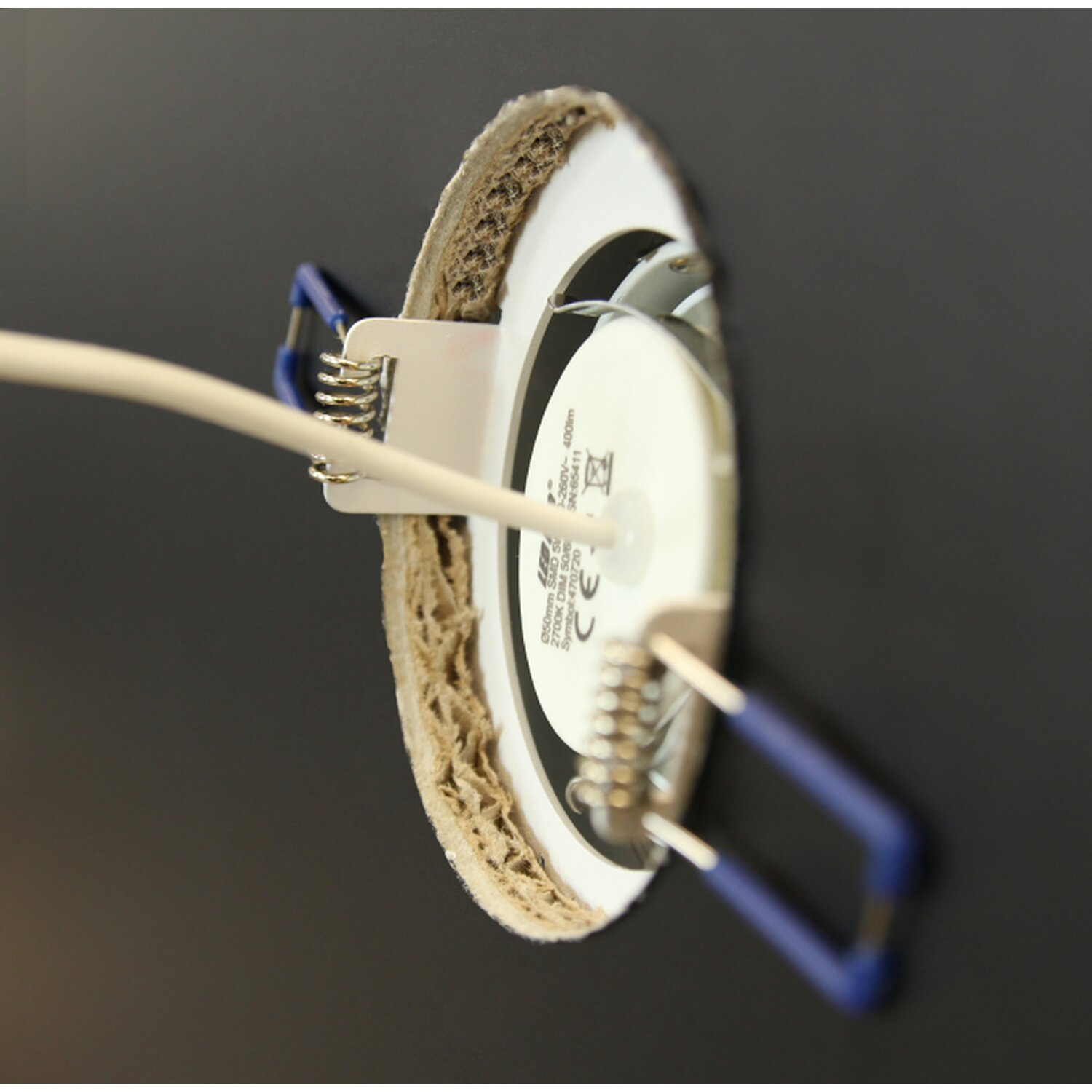 Eine LED-Leuchte ist in einer schwarzen Decke installiert. Kabel und Halterungen sind nah zu sehen.