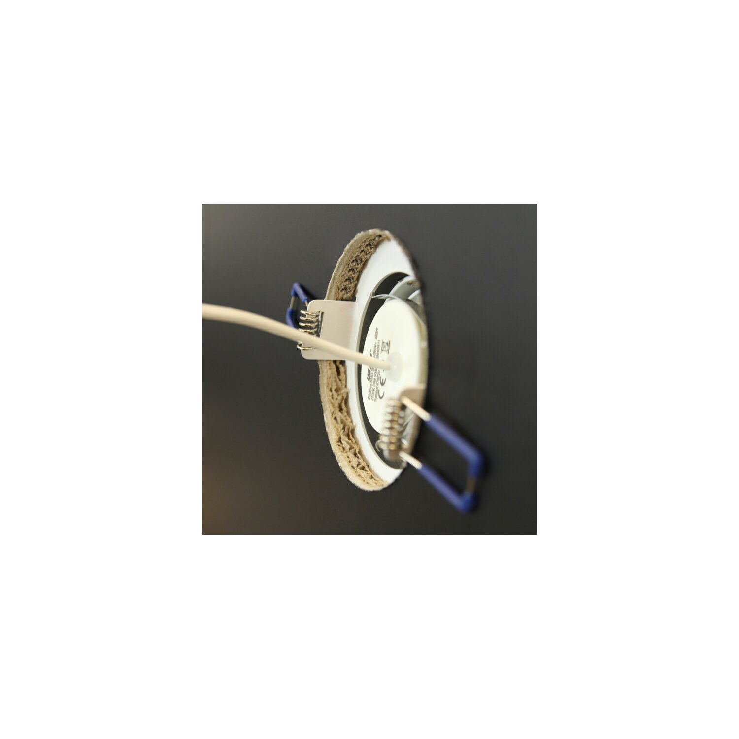 Nahaufnahme einer kreisförmigen Leuchte. Ein weißes Kabel erstreckt sich von der Leuchte.