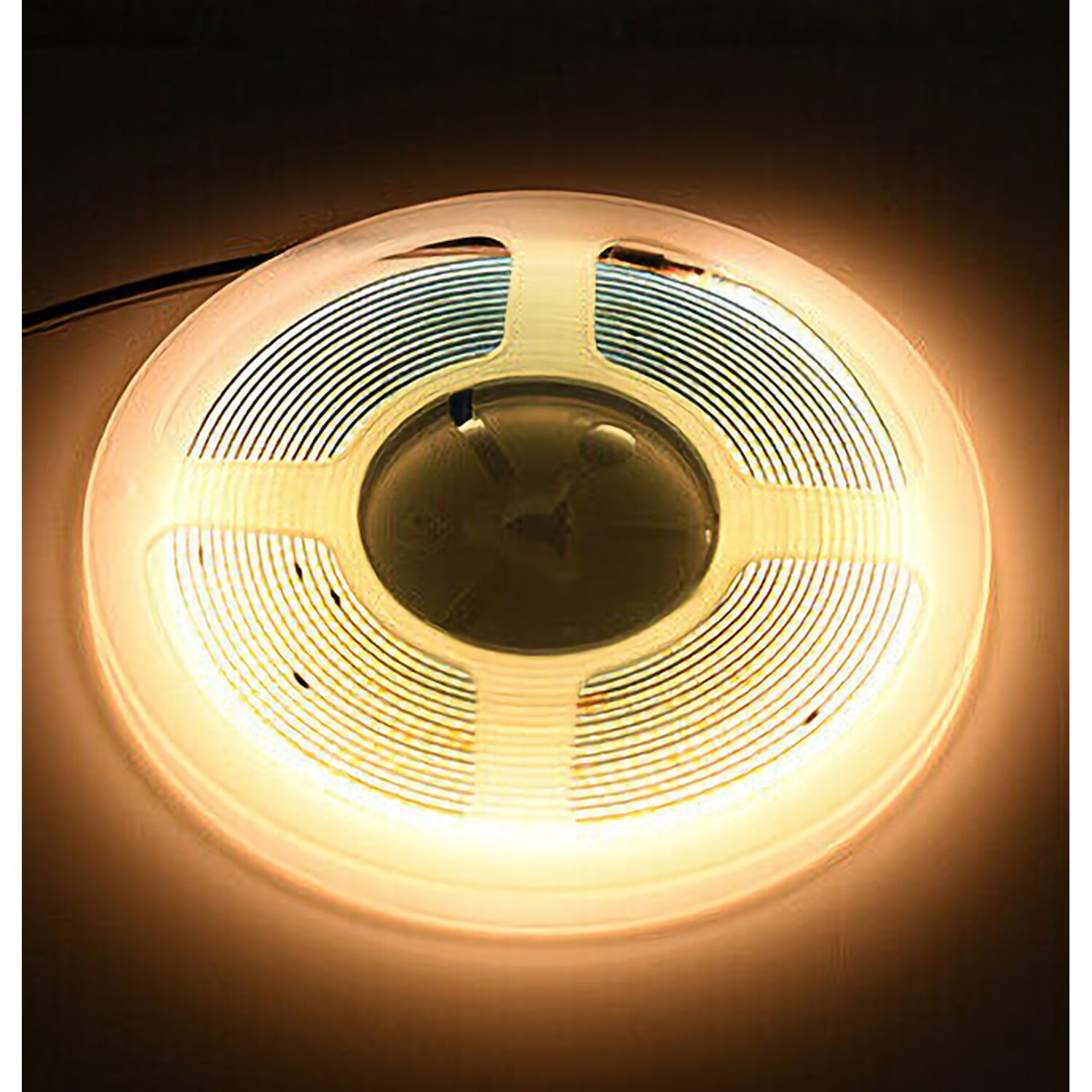 Ein aufgerolltes LED-Band, das warmes Licht ausstrahlt, ist sichtbar. Der Hintergrund ist ein dunkler, undefinierter Raum.