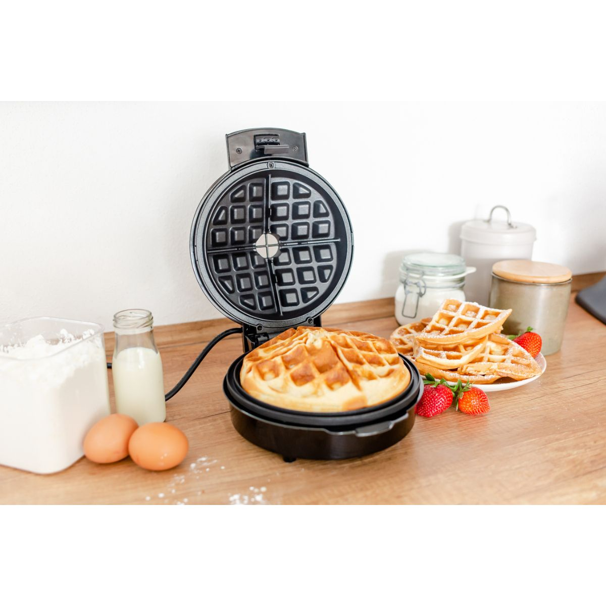 Ein Waffeleisen mit Waffel und Zutaten auf einem Tisch.