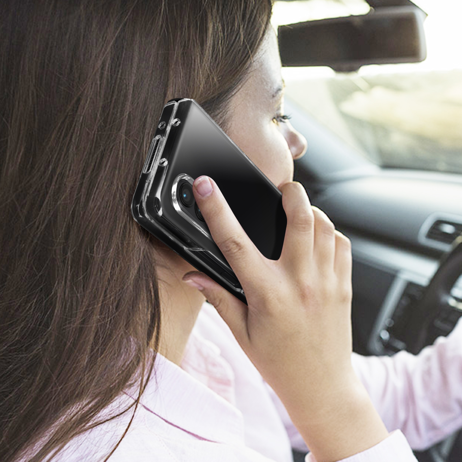 Una donna in macchina che parla al telefono. Il telefono è in una custodia trasparente.