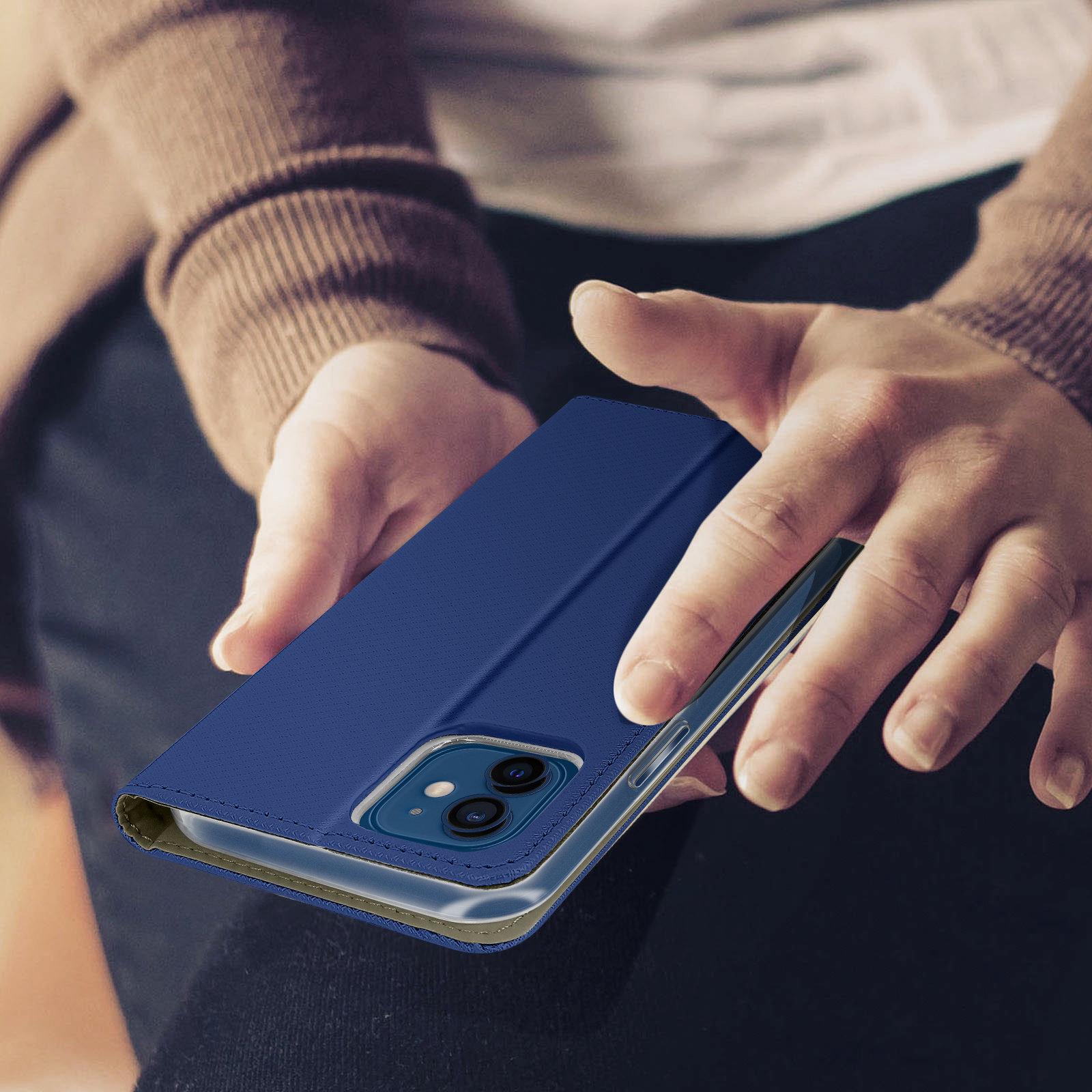 Een blauwe telefoonhoes met een telefoon erin, vastgehouden in handen. De achtergrond is vaag.