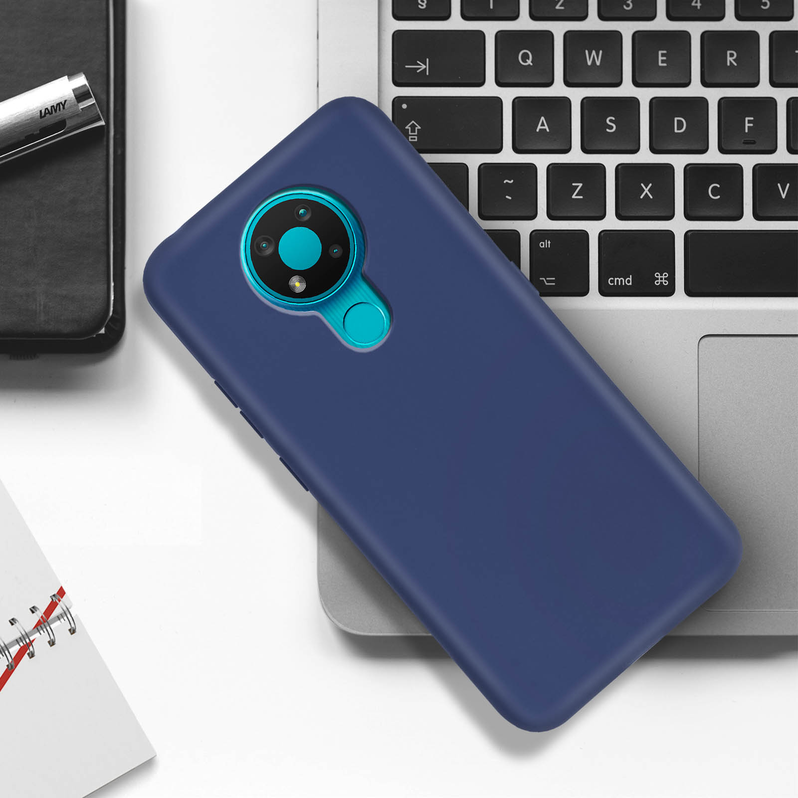 Custodia per telefono blu con fotocamera su una tastiera di un laptop. Tavolo bianco e laptop.