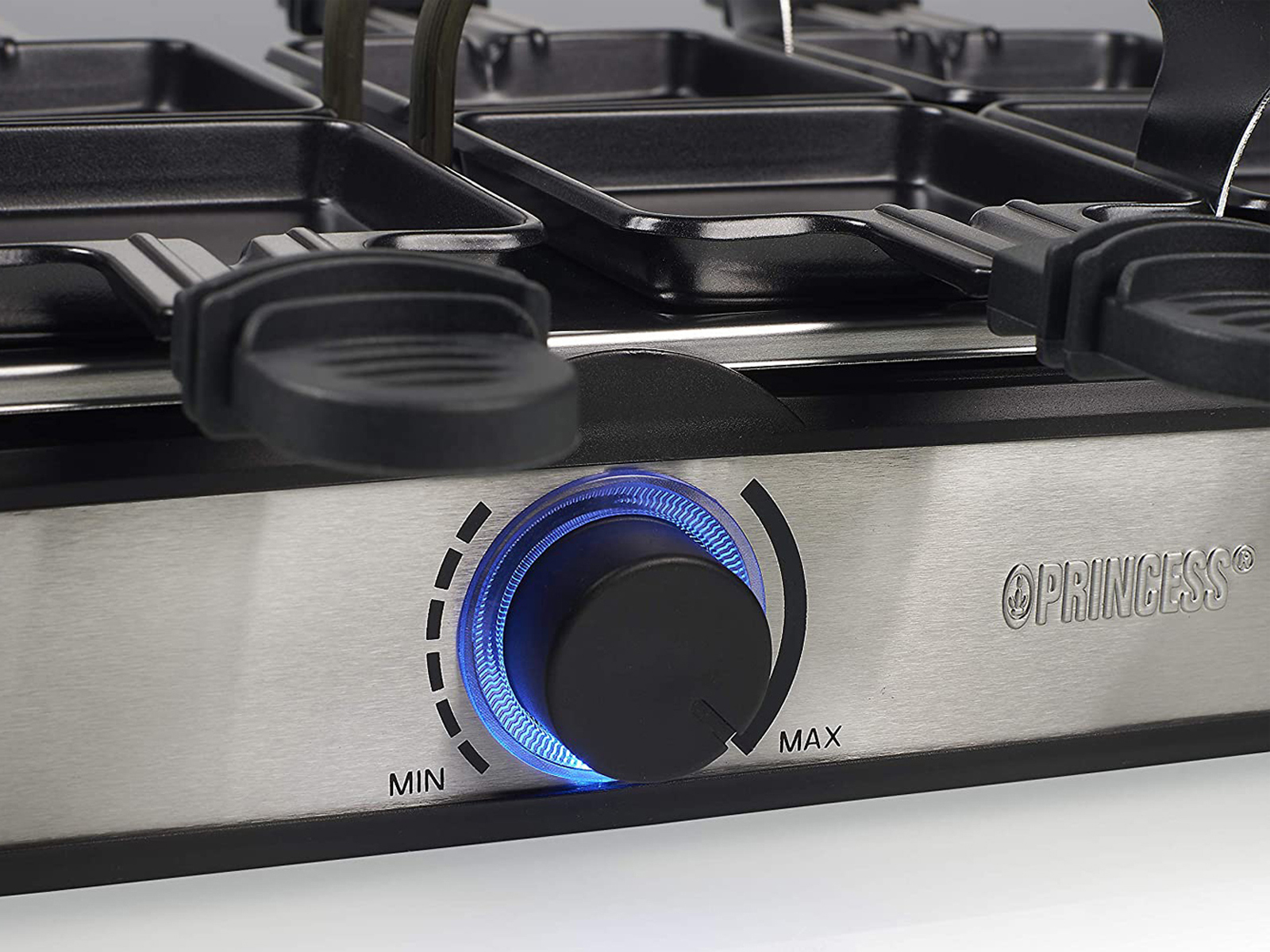 Grill do raclette z pokrętłem i patelniami. Z bliska.