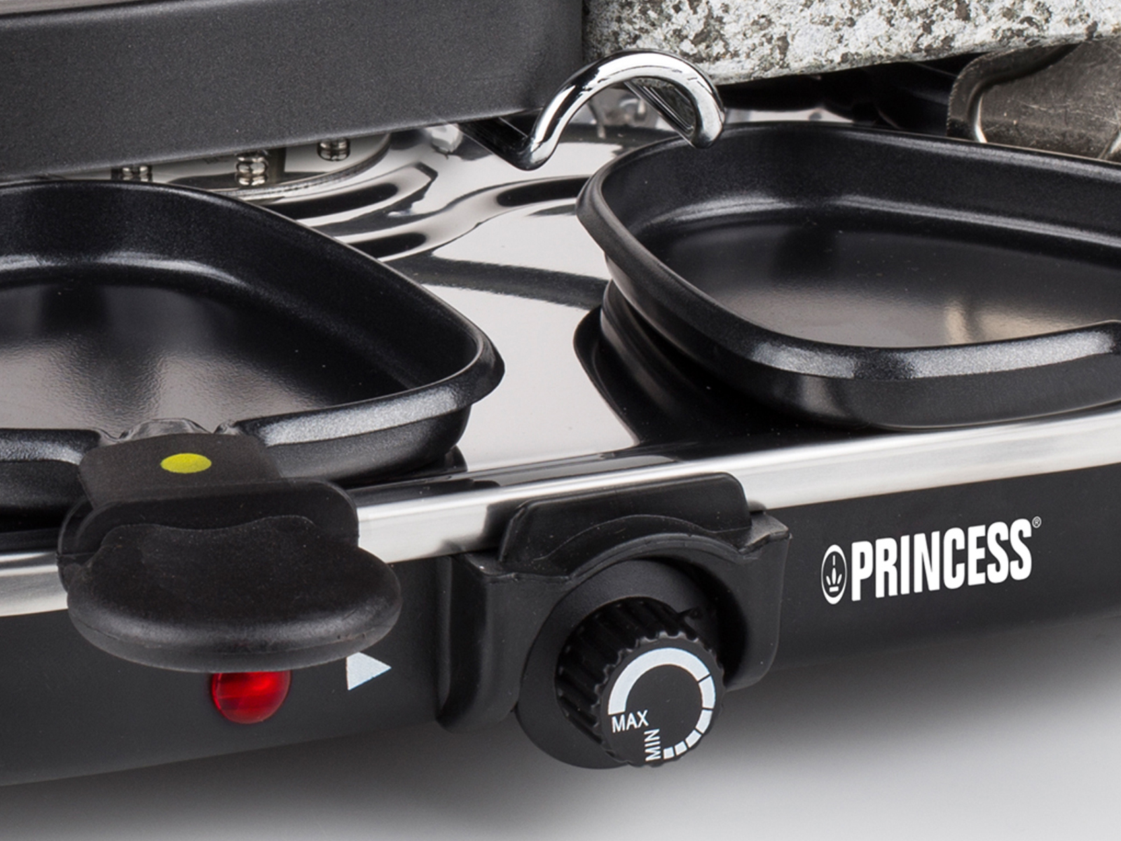 Nahaufnahme eines Raclette-Grills. Er hat schwarze Pfannen und einen Temperaturregler.