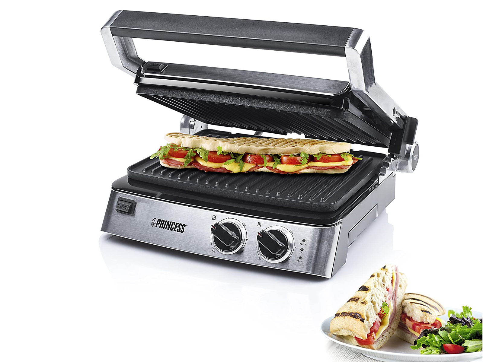 Silberner Panini-Grill mit einem Panini darin, außerdem zwei Paninis auf einem Teller mit Salat.