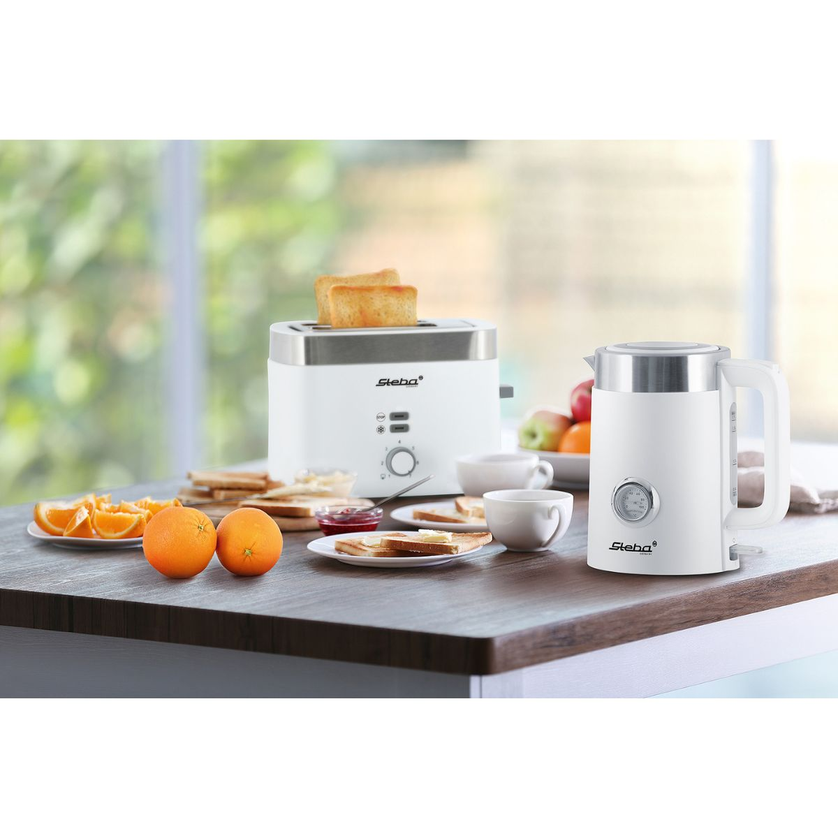 Frühstücksszene: Toaster mit Toast, Wasserkocher, Orangen und Lebensmittel auf einer Theke, in der Nähe eines Fensters.