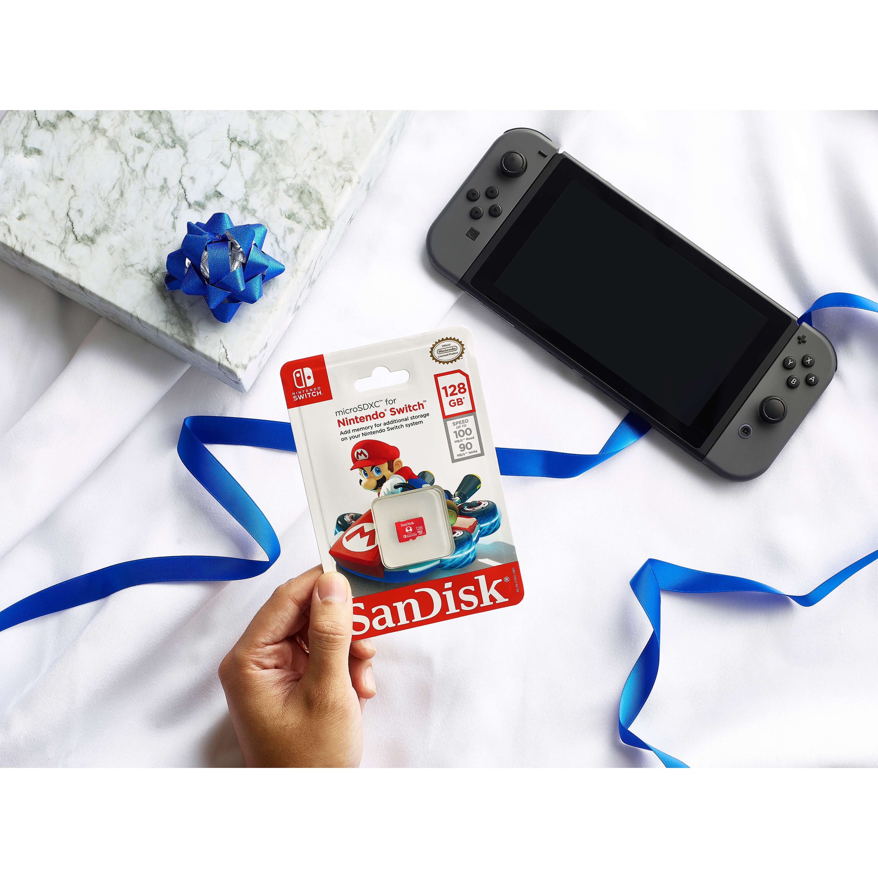 Una Nintendo Switch con una scheda di memoria SanDisk e una confezione regalo.