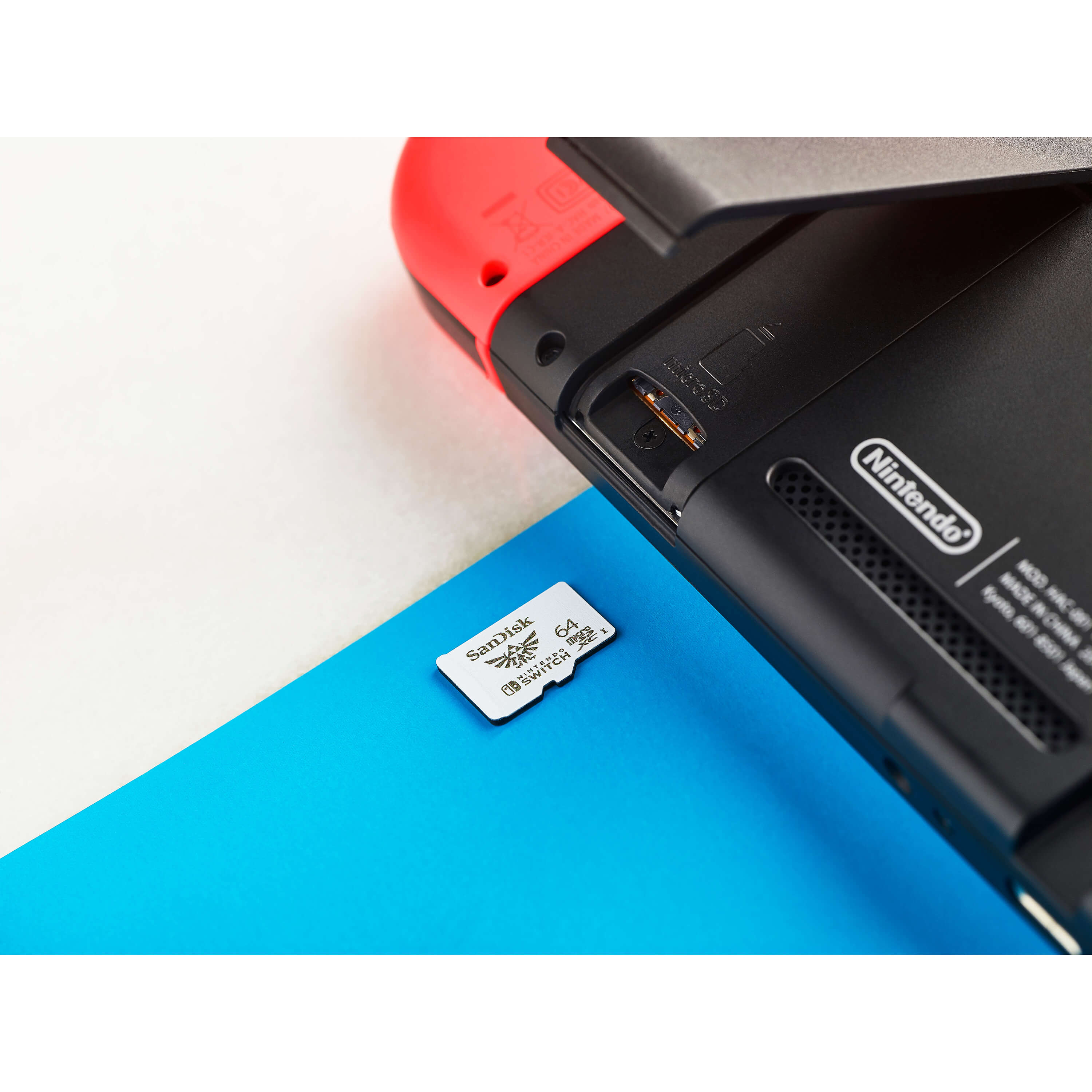 Eine SanDisk microSD-Karte liegt auf einer blauen Oberfläche neben einer Nintendo Switch Konsole.