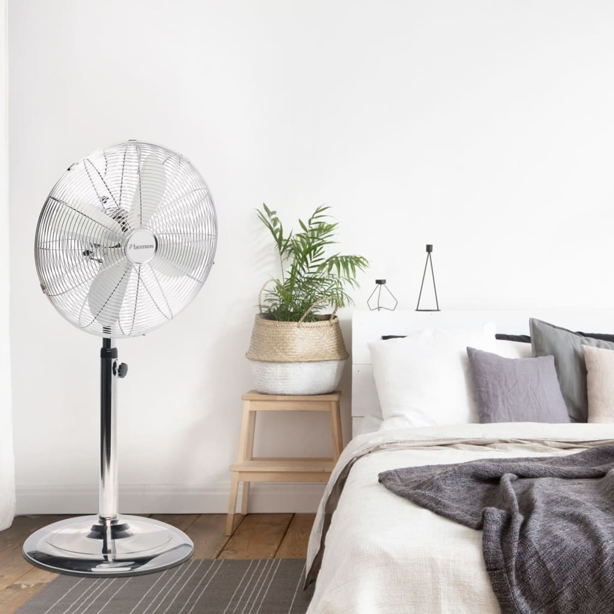 Ventilatore argentato in una camera da letto con un letto.