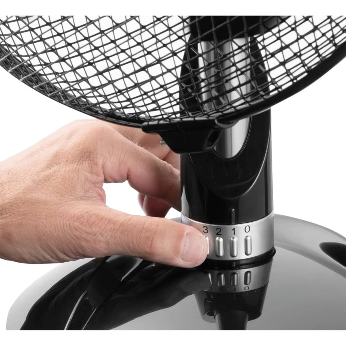 La mano di una persona che cerca di regolare il selettore di velocità su un ventilatore nero e argento.